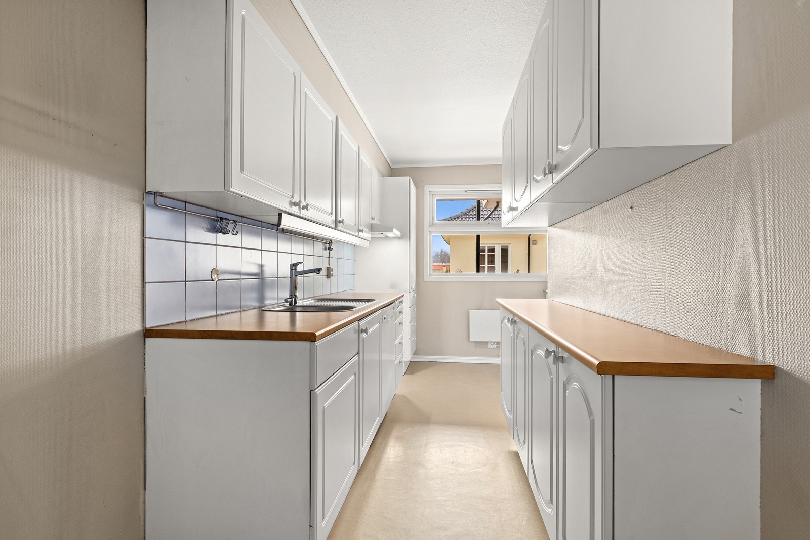 Det er fliser over deler av benken og opplegg til oppvaskmaskin. Galleribilde