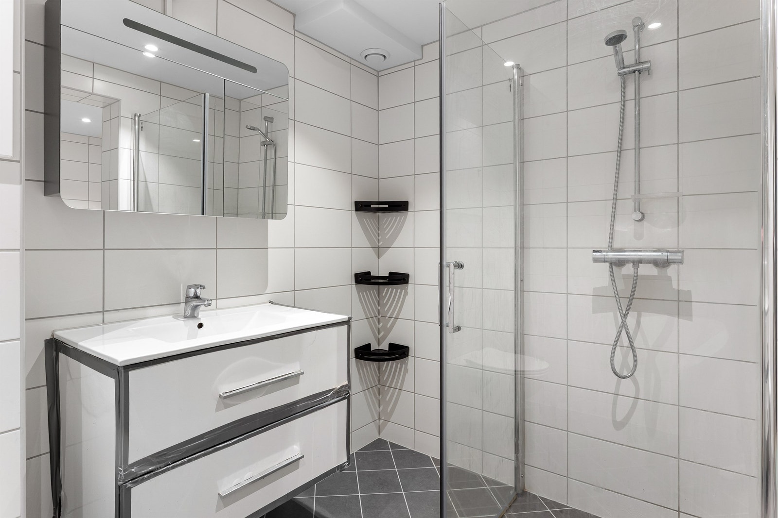 Dusjhjørne med svingbare glassdører og innfelte downlights i taket. Galleribilde