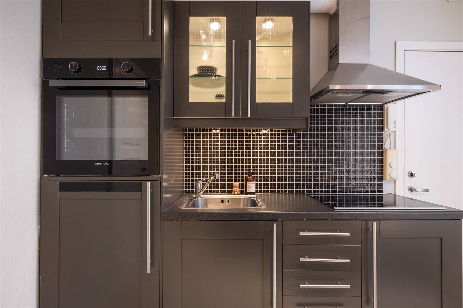 Kjøkkeninnredning fra IKEA med profilerte fronter, benkeplate i laminat og integrerte hvitevarer med platetopp, nyere stekeovn og kjøleskap. Galleribilde