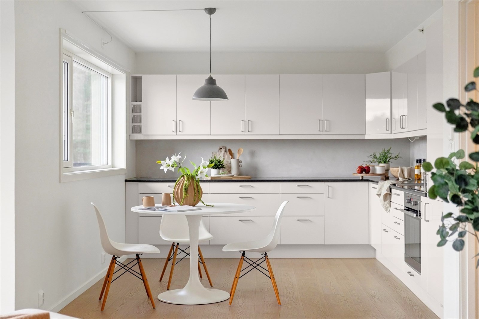 Tidløs kjøkkeninnredning med lyse slette fronter, laminat benkeplate og kjøkkenvask i rustfritt stål Galleribilde