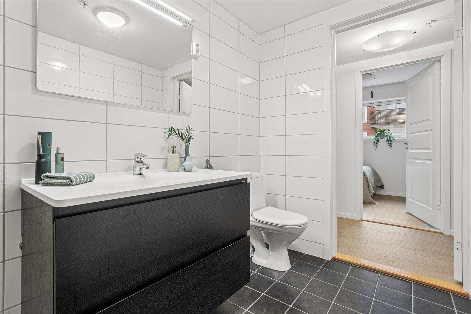 Baderommet er innredet med toalett, dusjhjørne, servant med møblement og speil m/ belysning Galleribilde