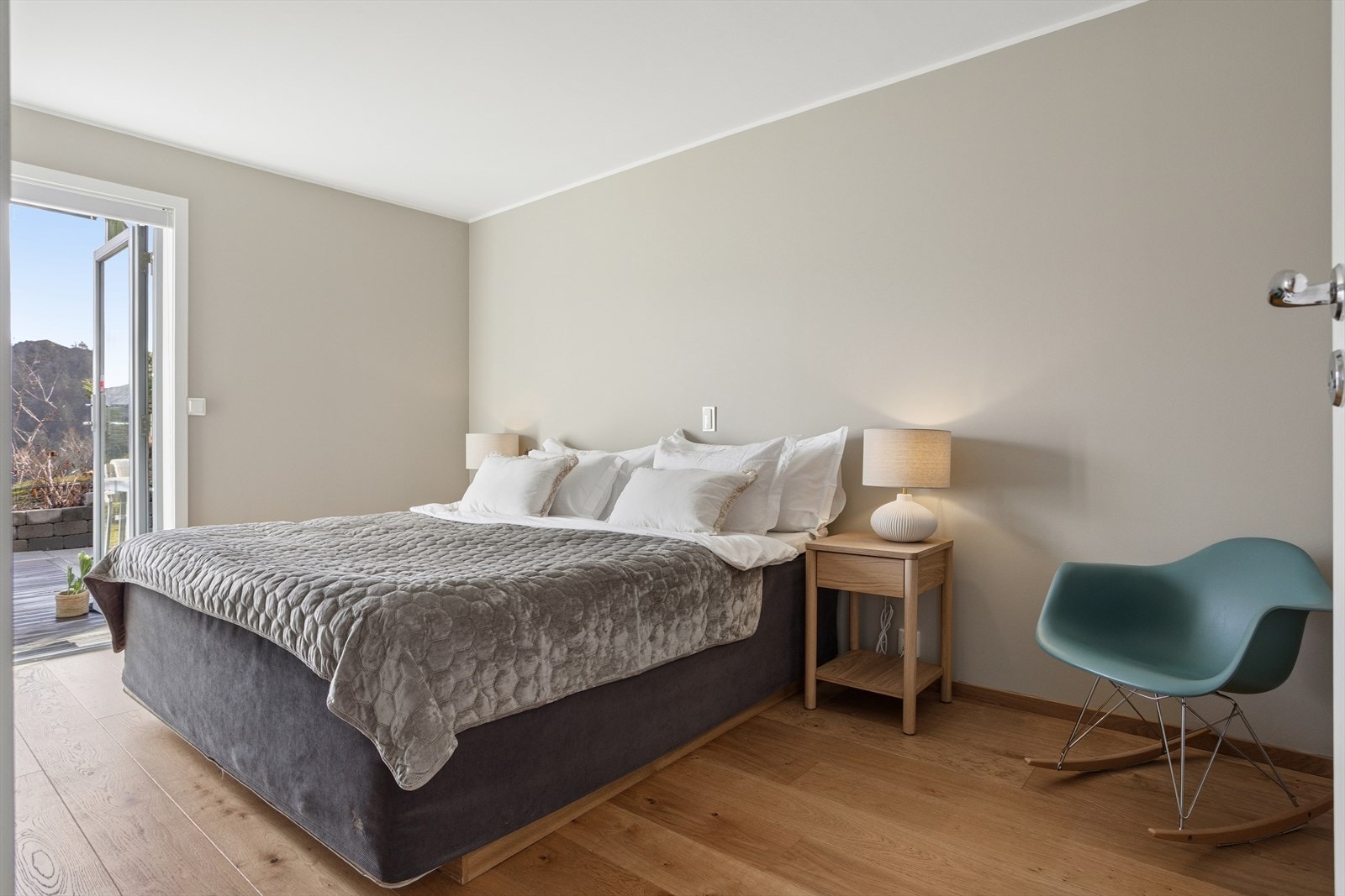 Ett av soverommene utmerker seg med direkte utgang til hagen og det flotte terrassedekket, noe som gir en egen privat sone med nærhet til uteområdene. Galleribilde