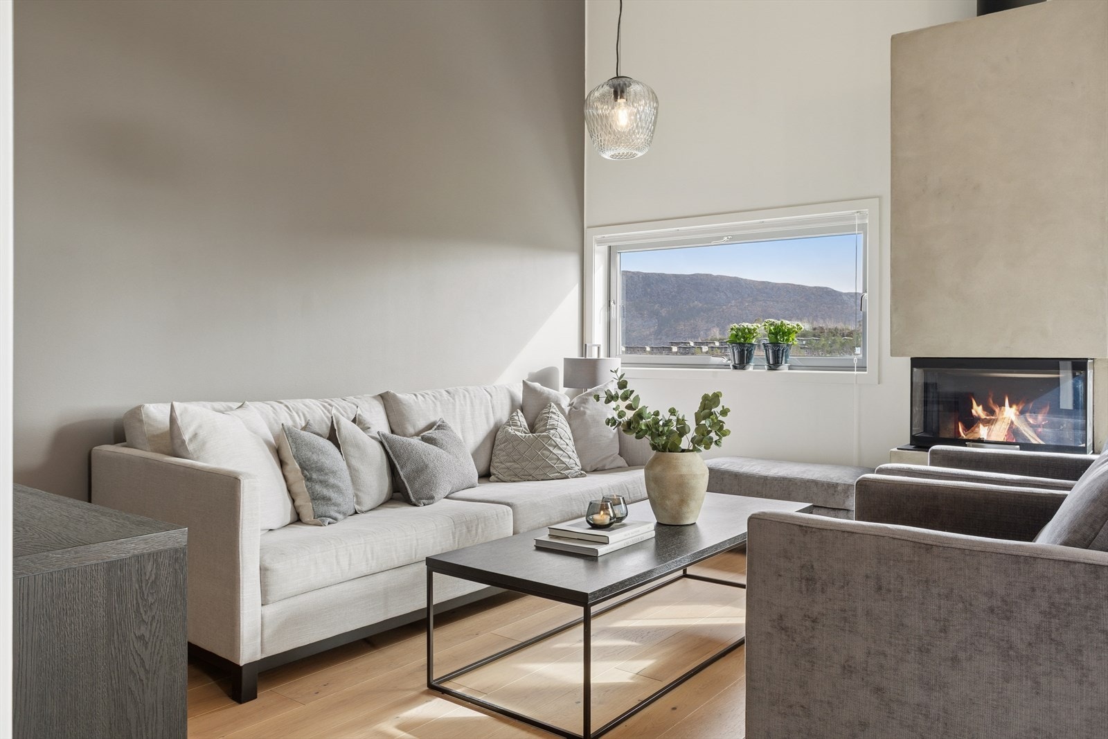 Stuen byr på god plass til både sofagruppe og spiseplass, og den moderne peisovnen fra 2021 står som et naturlig samlingspunkt på kjøligere dager. Galleribilde