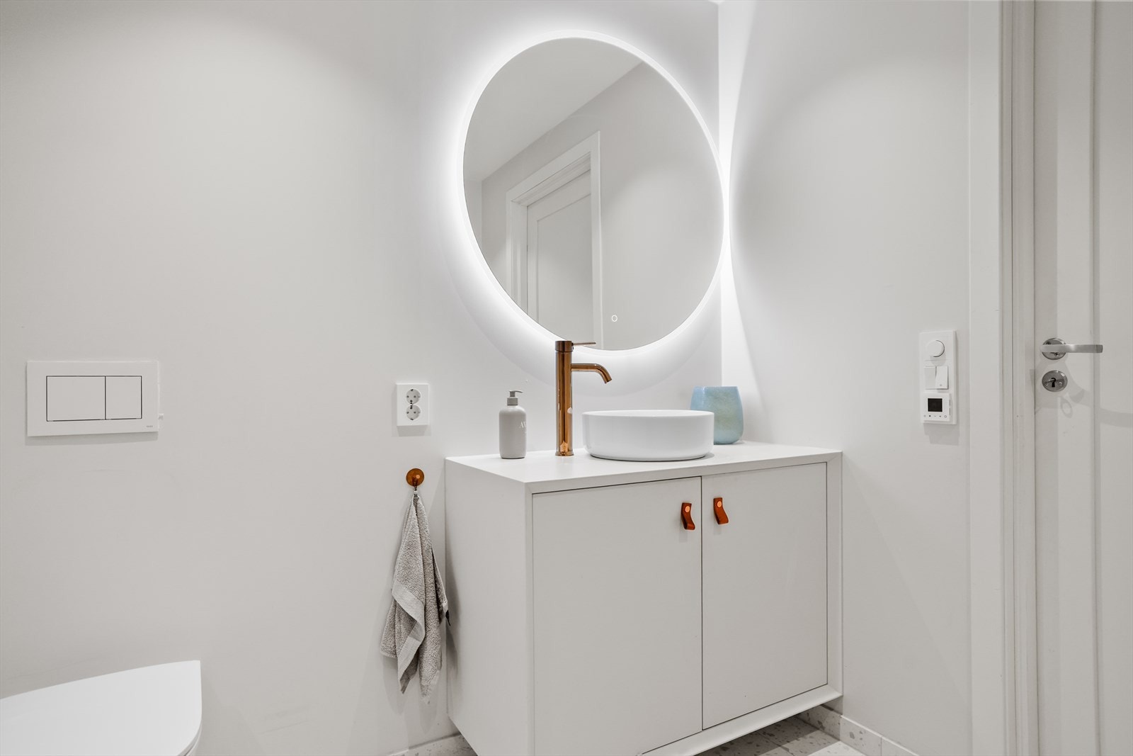 Veggene er delvis flislagt kombinert med malte plater, noe som gir en fin balanse mellom det praktiske og det estetiske. Gulvet er belagt med fliser og har elektriske varmekabler som gir god komfort og en lun følelse, spesielt på kjølige dager. Galleribilde