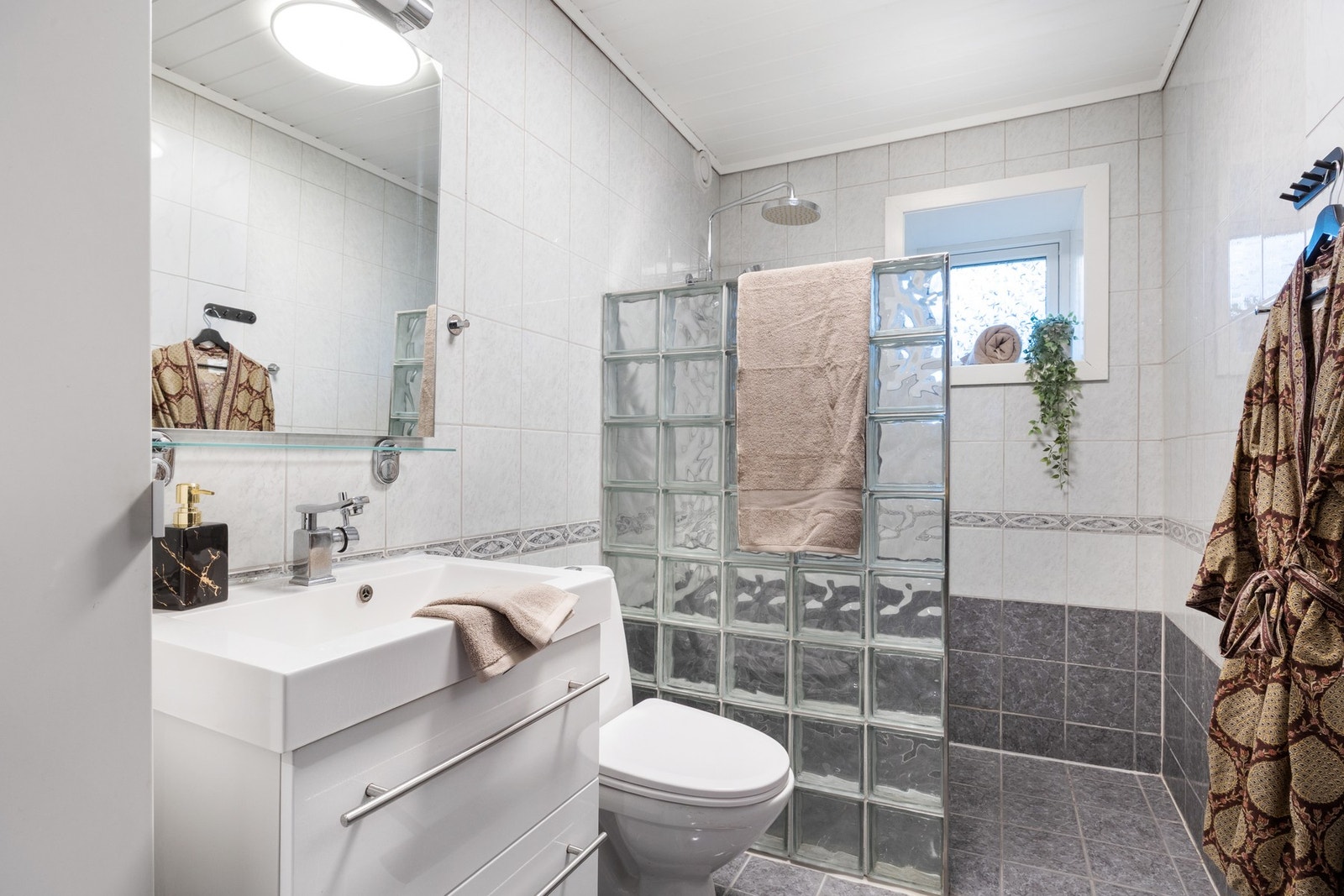 Badene fremstår tidløse med lys innredning og flislagte gulv og vegger Galleribilde