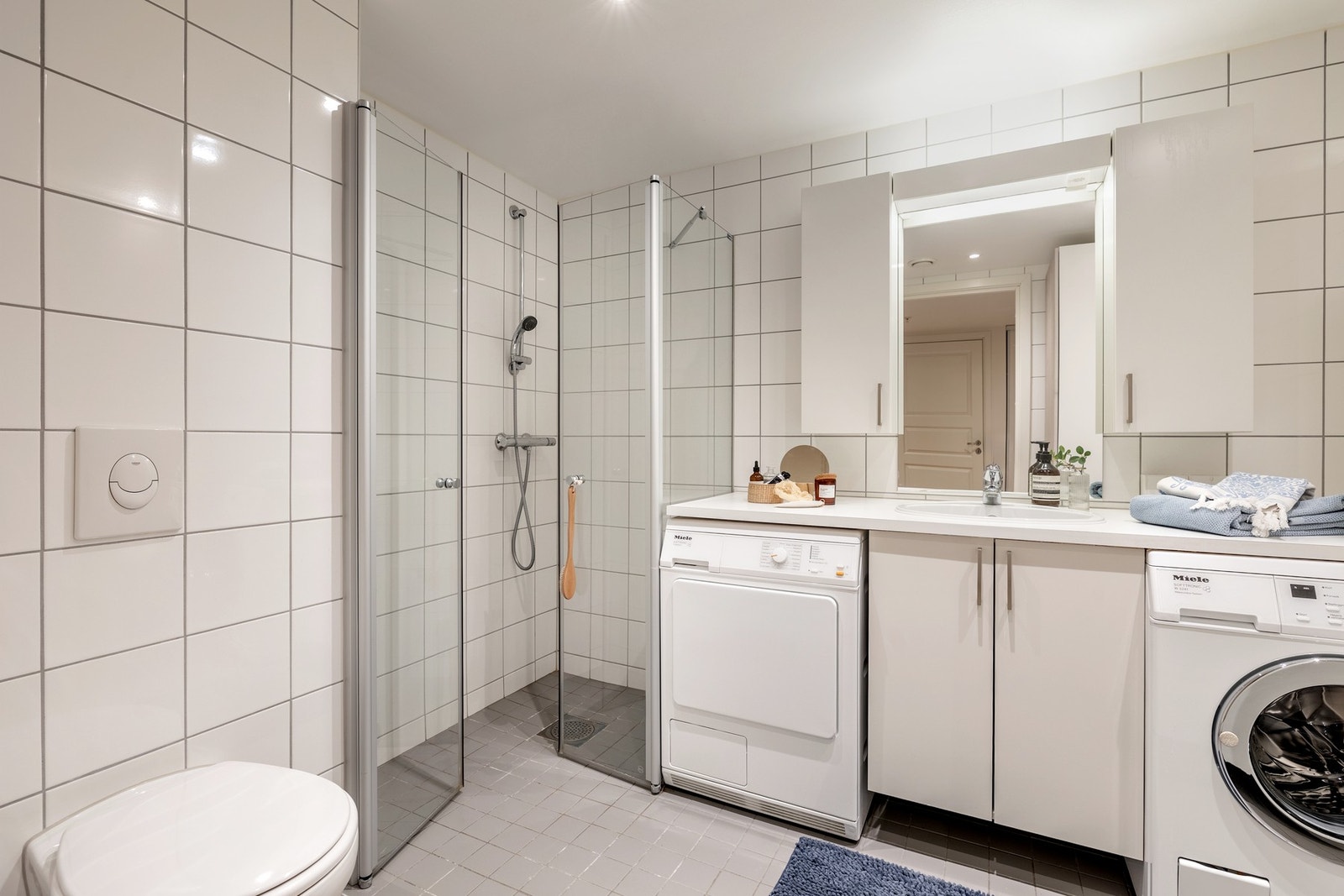 Innredningen består av laminert benkeplate med nedfelt servant, speil og overskap på vegg over servant, vegghengt toalett og dusjhjørne med svingbare glassdører. Galleribilde