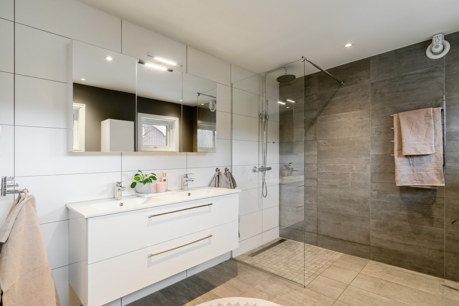 Romslig og stilrent bad innredet med stilrene overflater, dusjsone med glassvegg, dobbel servant og toalett. Rommet måler 8,5 m². Galleribilde