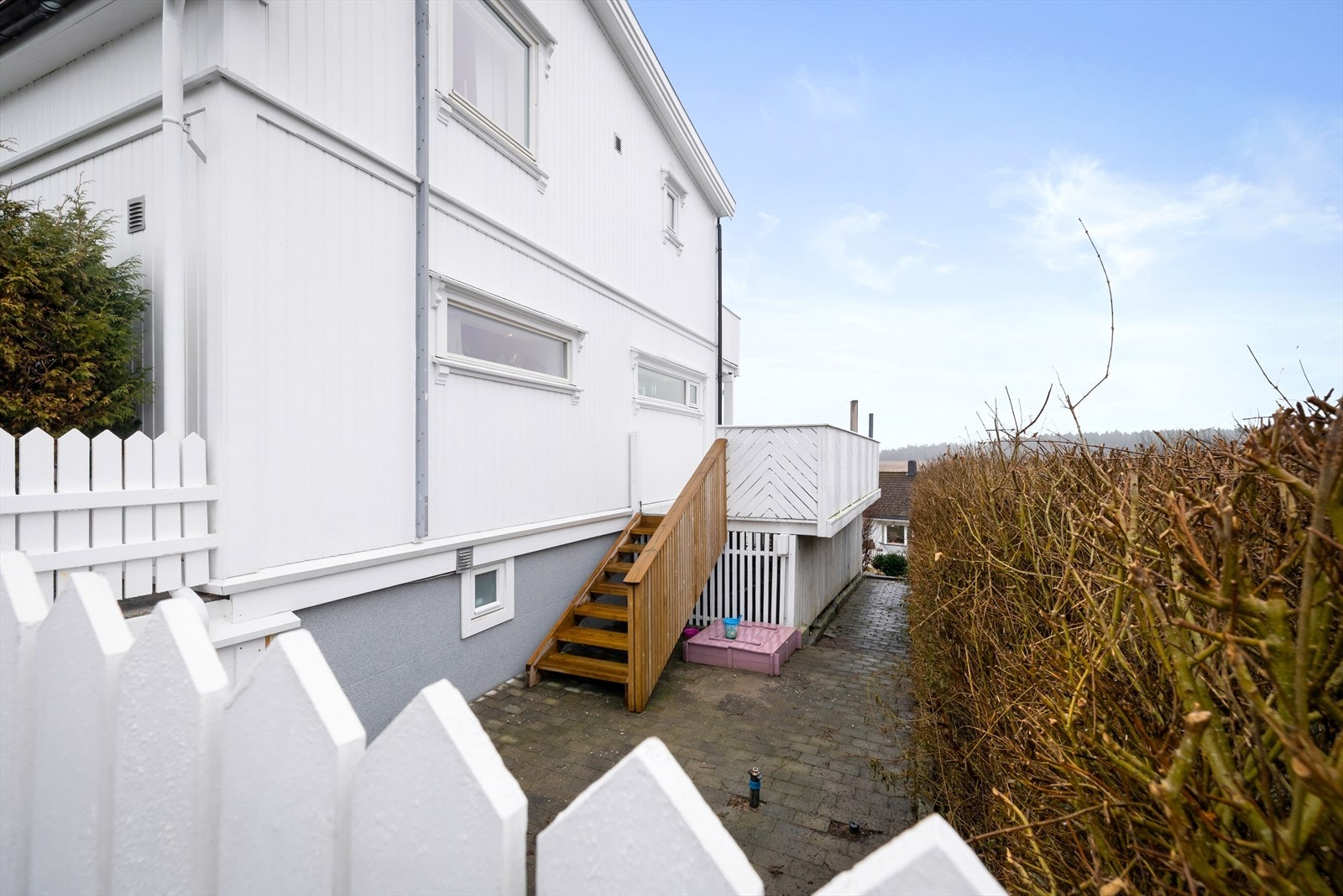 Trapp ned fra terrassen til en skjermet uteplass på siden av huset. Galleribilde