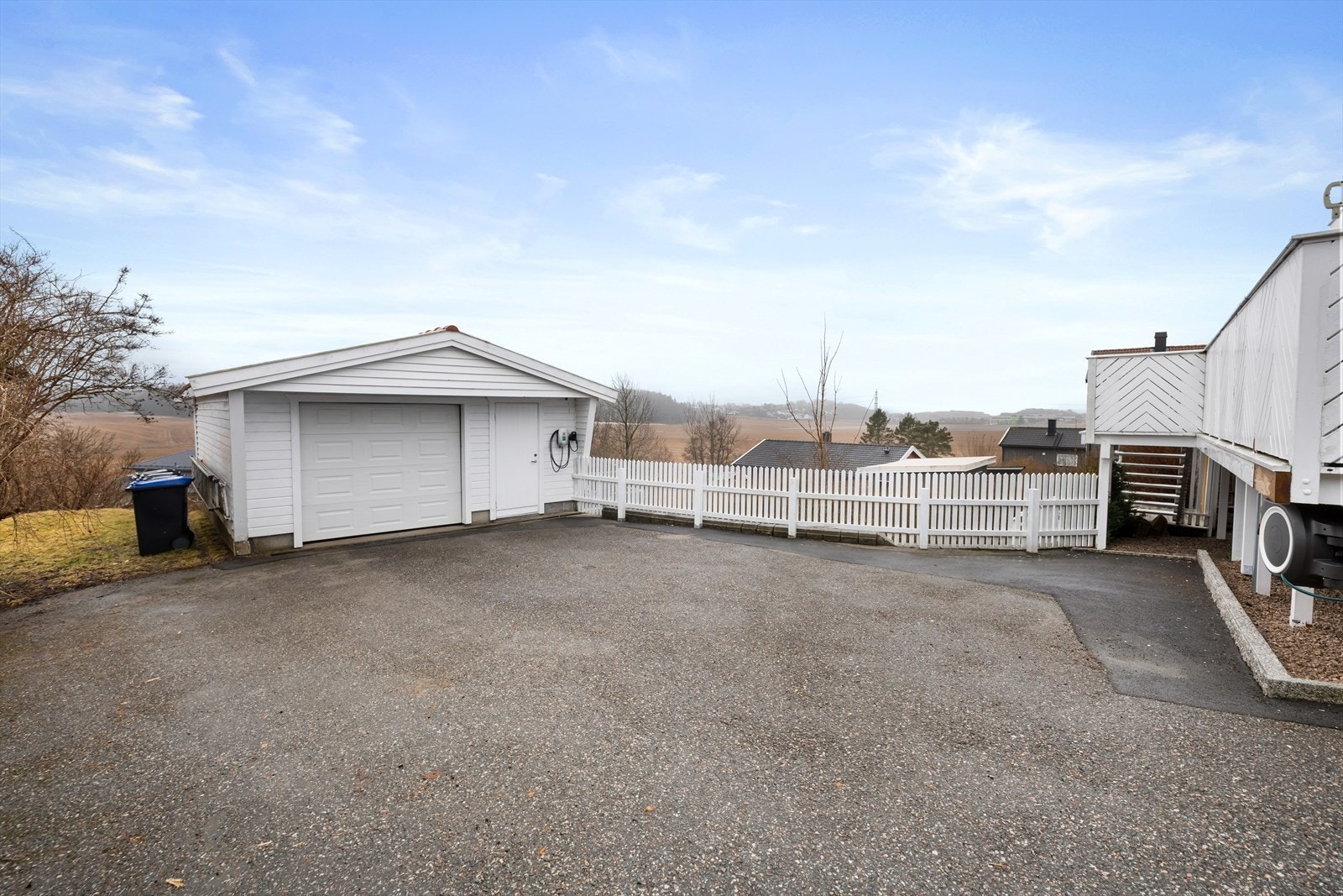 Stor, asfaltert gårdsplass med rikelig av biloppstillingsplasser og en frittstående garasje. Galleribilde