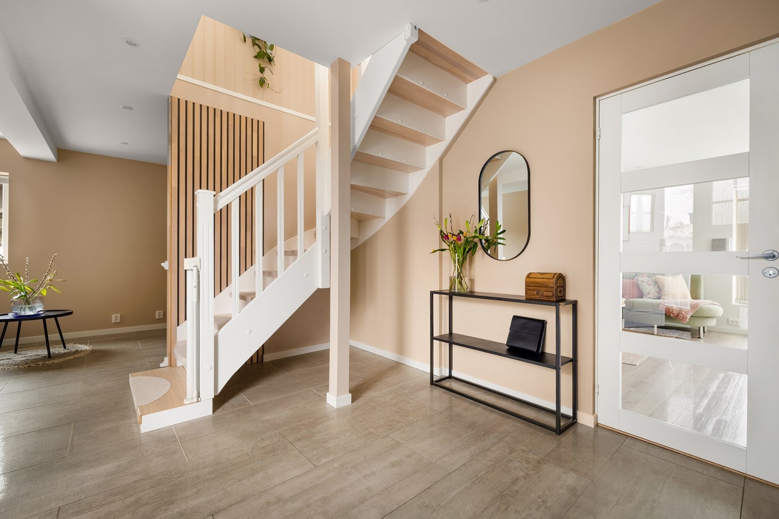 Velkommen inn i en romslig entré med trapp til andre etasje og inngang til en egen stuedel. Galleribilde