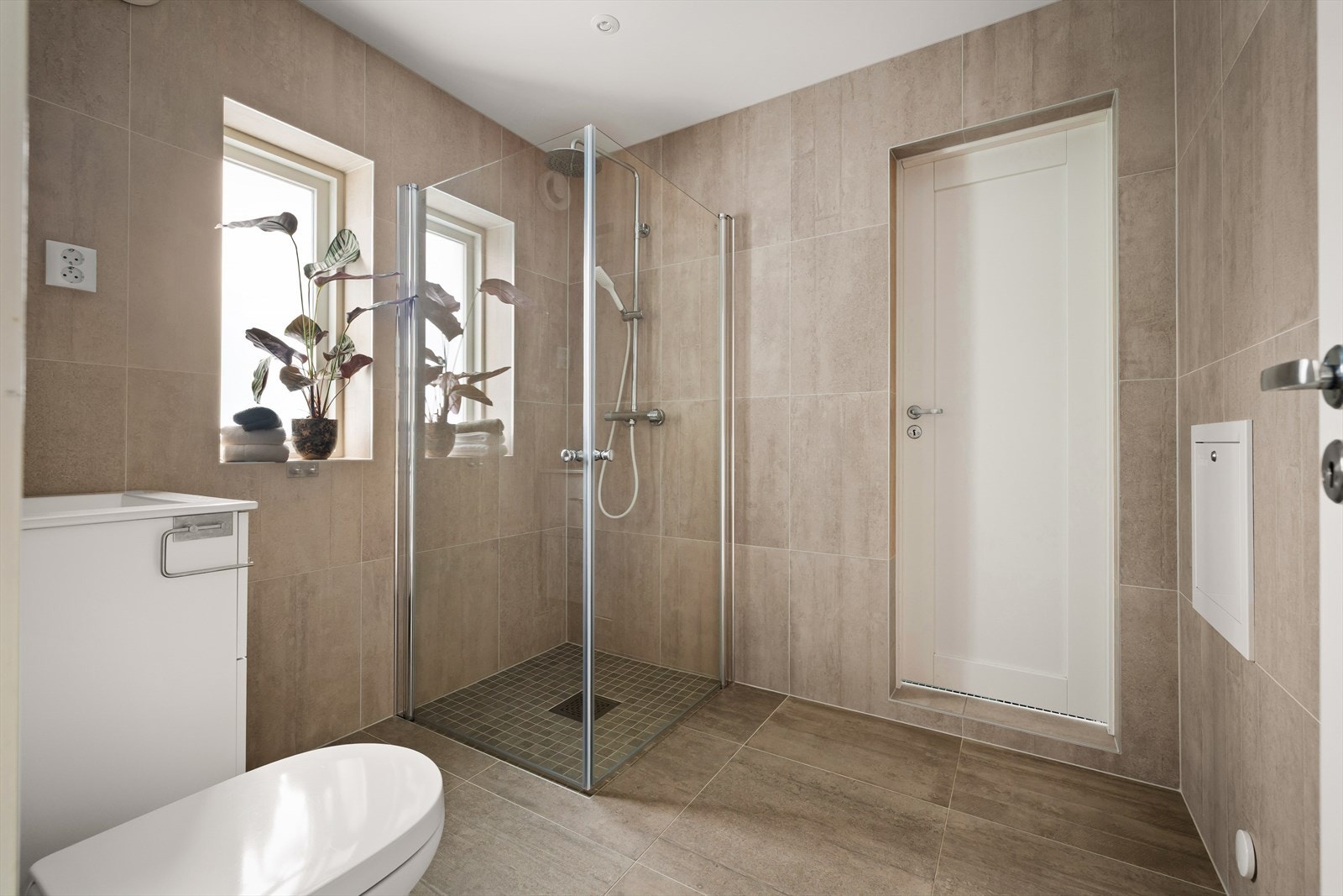 Pent, flislagt bad i første etasje med dusjhjørne med innfellbare dører. Galleribilde