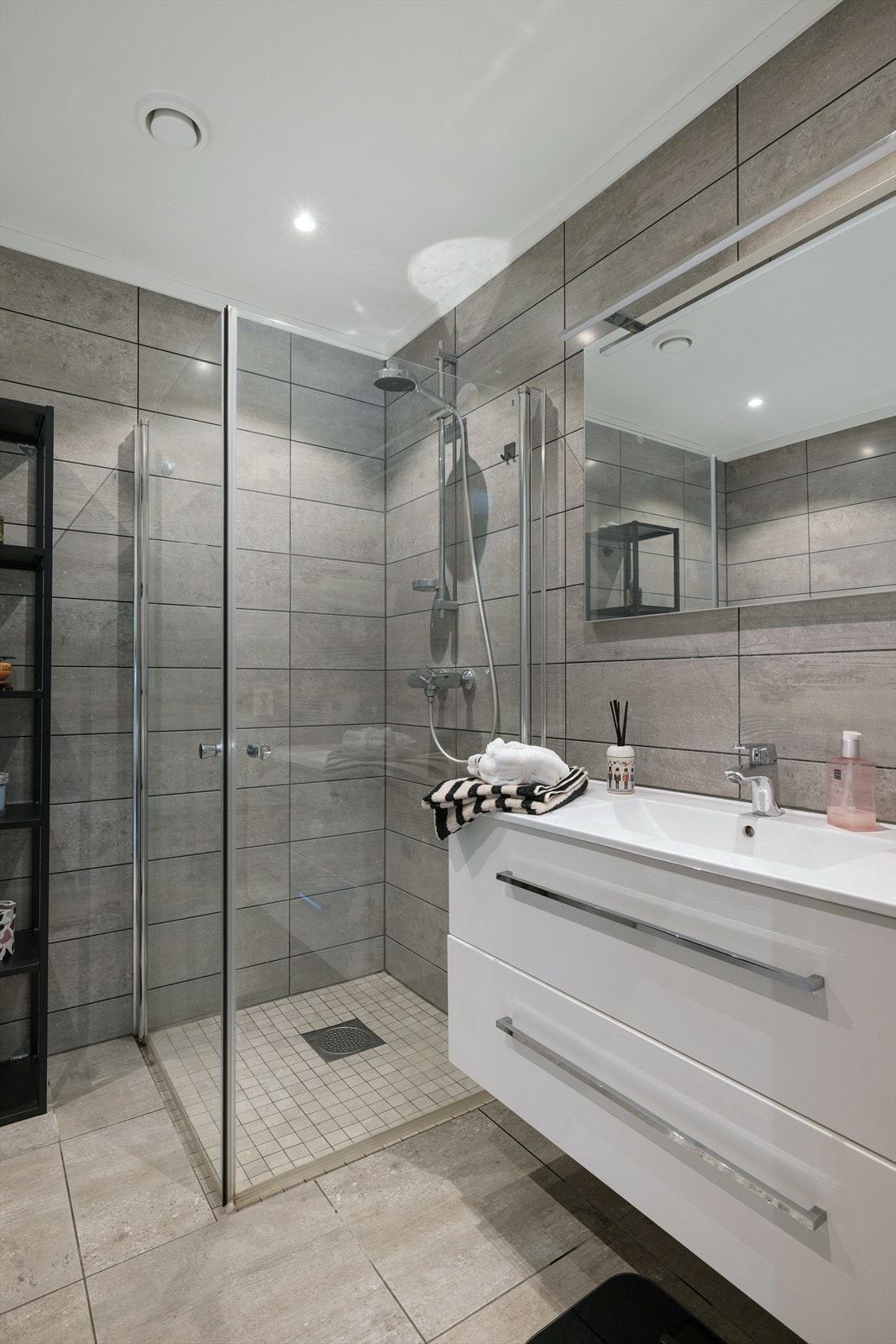 Innredningen inkluderer servant, toalett og et dusjhjørne med innfellbare glassdører. Galleribilde