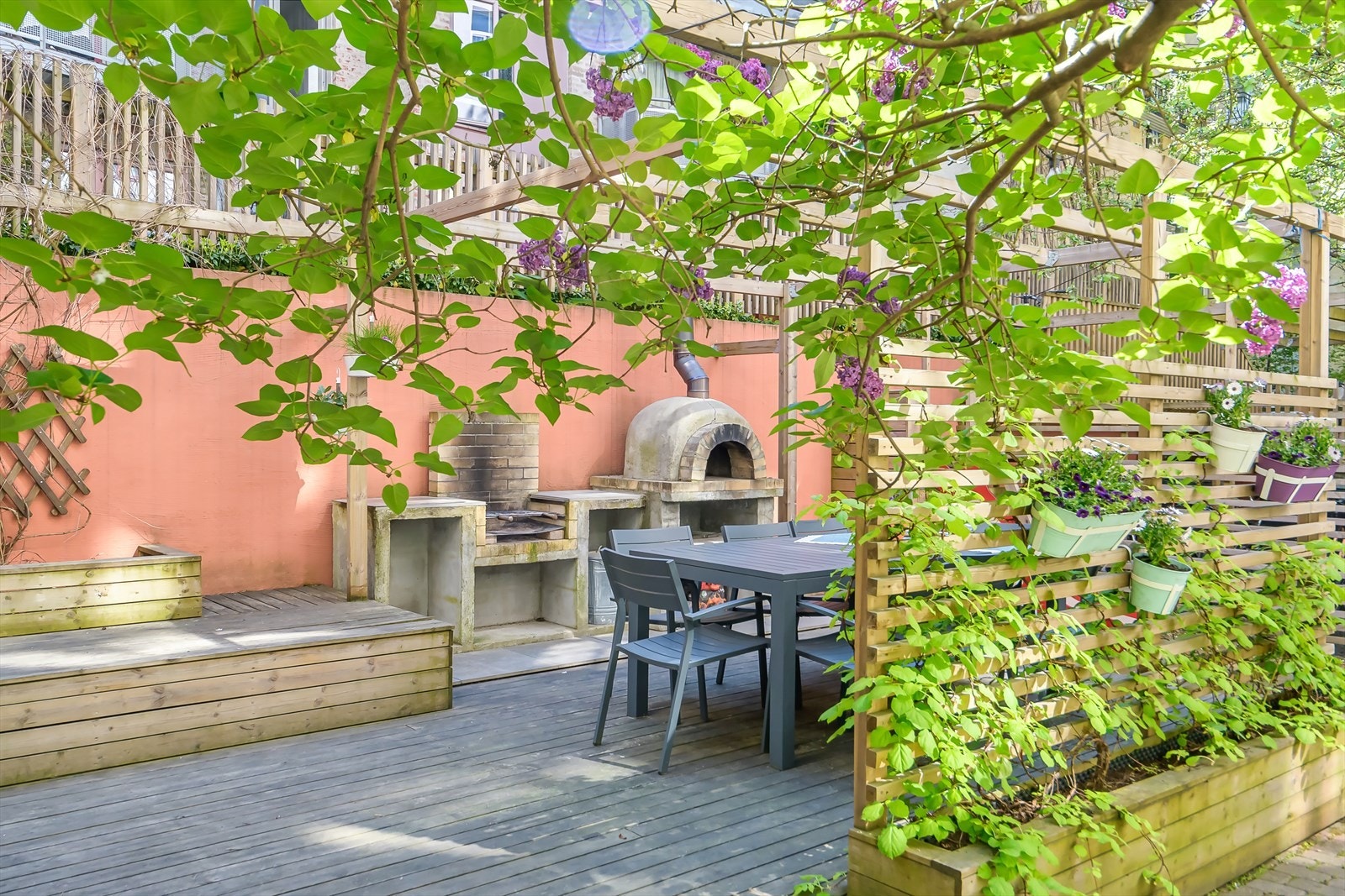 Bakgården er felles uteområde, og er opparbeidet med flott beplantning, belegningstein på bakken og treplatting med sittegrupper Galleribilde