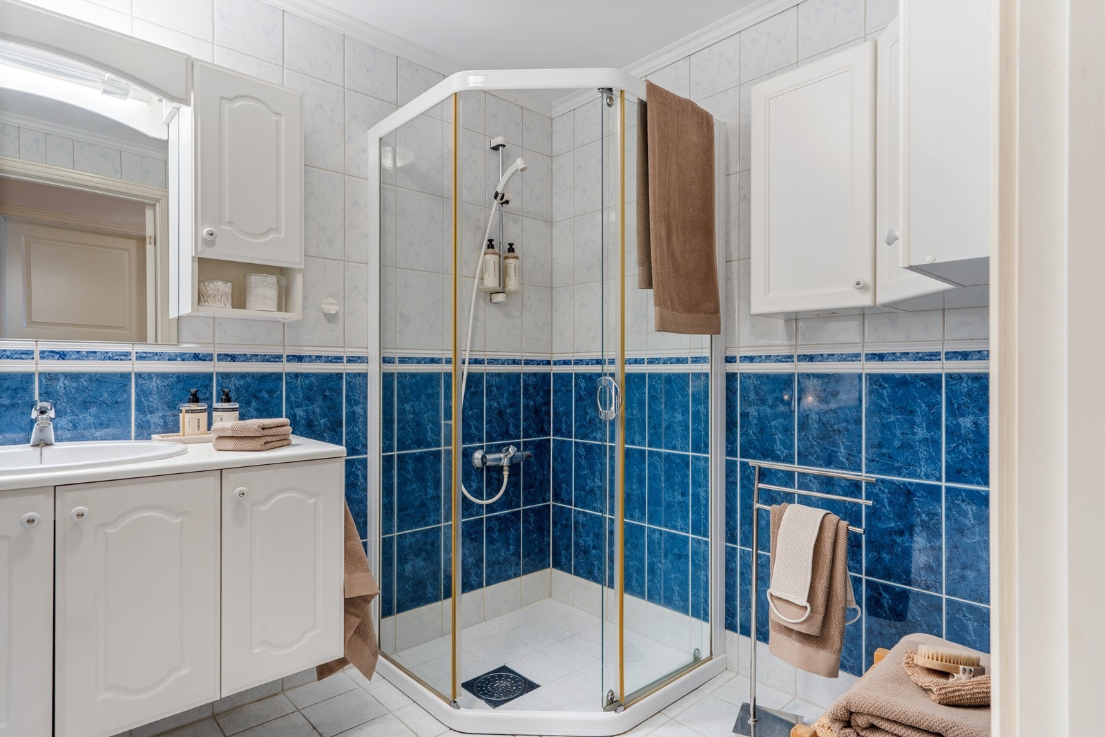 Badet er helfliset og utstyrt med elektriske varmekabler i gulvet. Rommet har baderomsinnredning med nedfelt servant, toalett og dusjkabinett Galleribilde