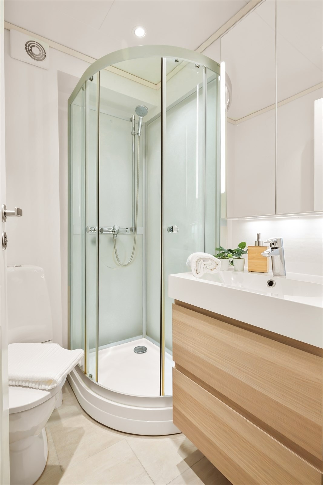 - Badet er innredet med laminerte fronter, heldekkende servant, speilskap med belysning, gulvstående toalett og dusjkabinett - Galleribilde