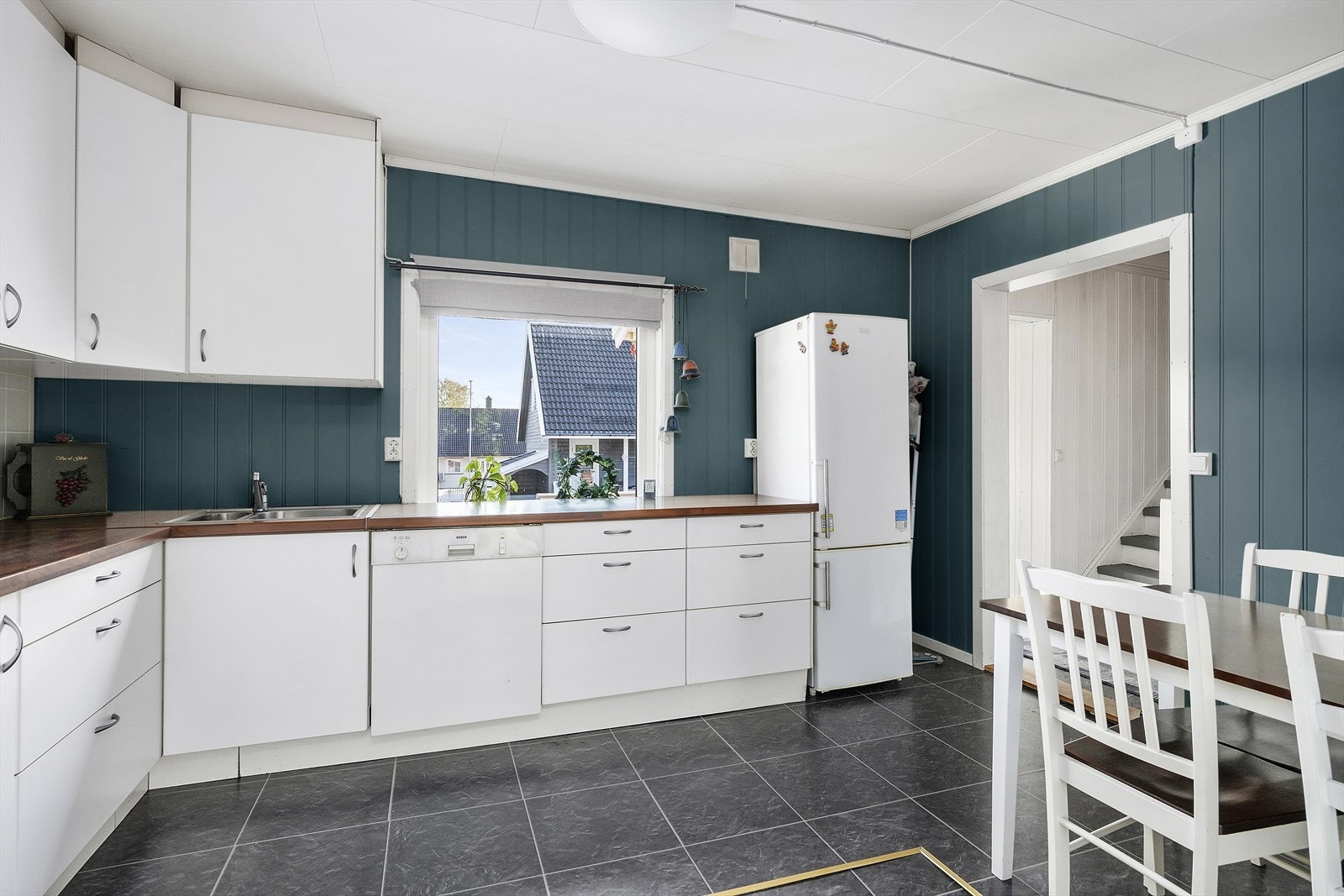 Funksjonelt kjøkken med hvite fronter, benkeplate i tre og spiseplass. En hyggelig sone for både matlaging og hverdagsmåltider. Galleribilde