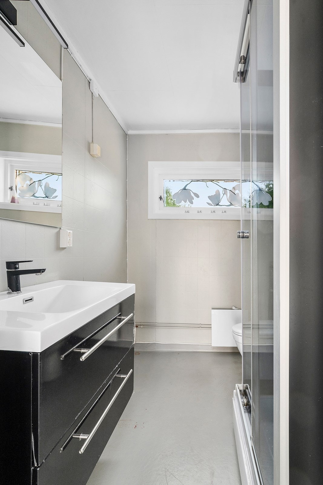 Badet fremstår som lyst og praktisk, med moderne servantinnredning, speil med god belysning og separat dusjkabinett. Et effektivt rom med alt du trenger i hverdagen! Galleribilde