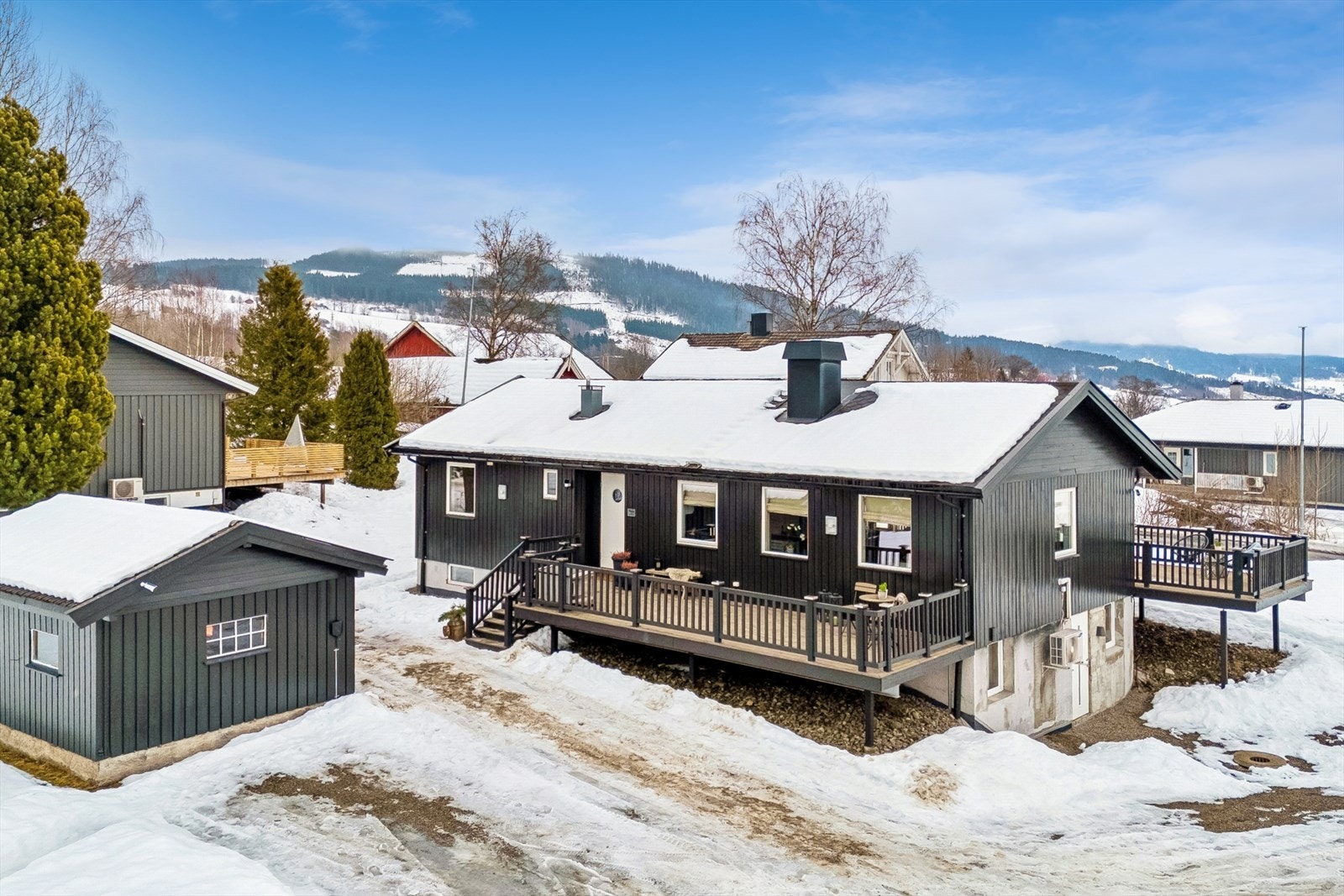 Eiendommen har en skrånende tomt på 937 m² med gruset gårdsplass og et praktisk uthus for lagring. Galleribilde