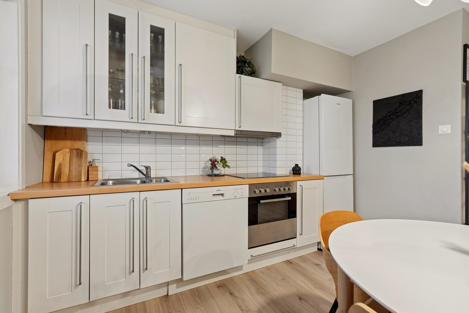 Kjøkkenet har hvite profilerte fronter, ovn, platetopp, ventilator, oppvaskmaskin samt frittstående kjøleskap/frys. Galleribilde