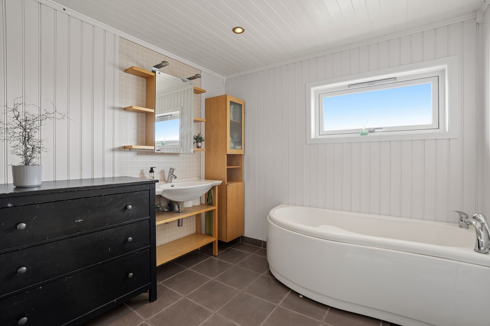 Rommet er komplett med badekar og baderomsinnredning. Malt panel i taket med innfelte spotlights gir en lun atmosfære. Galleribilde