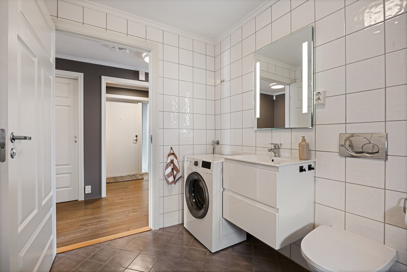 Badet inneholder heldekkende servant med underskap, speil med lys, vegghengt toalett, dusjhjørne og opplegg til vaskemaskin. Galleribilde