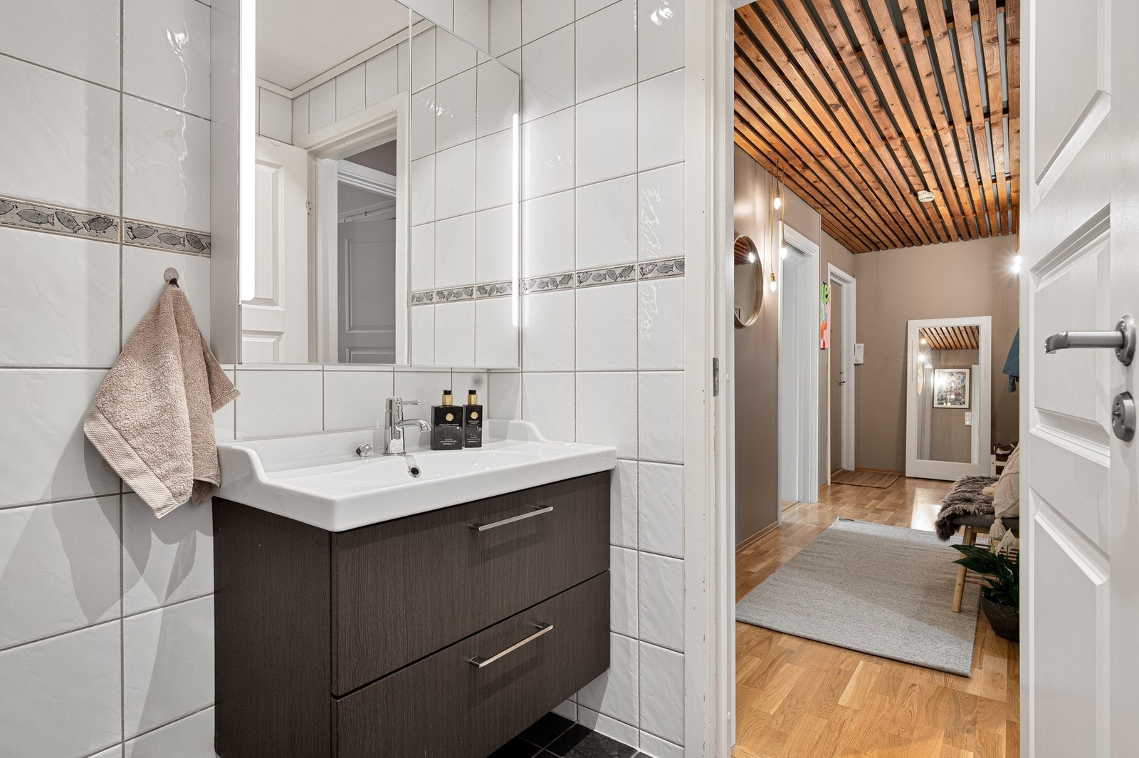 Badet er innredet med dusjhjørne, servant med underskap, speil og veggmontert toalett. Galleribilde