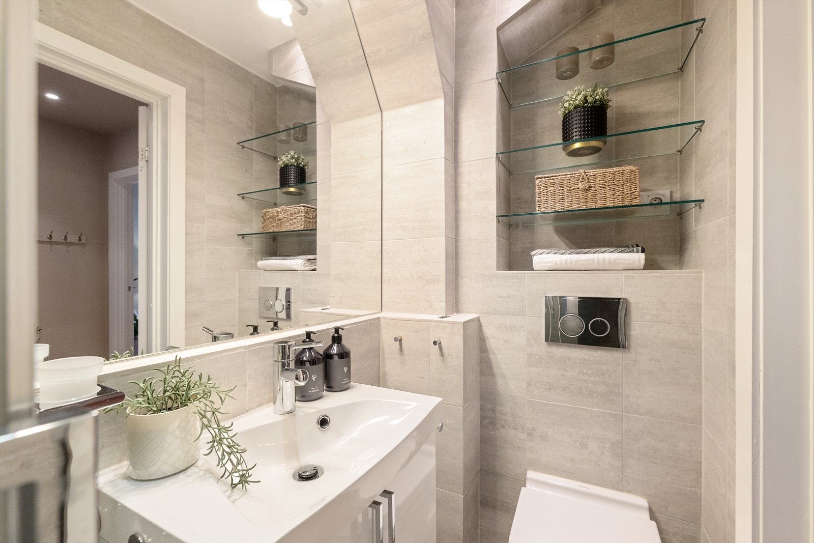 Badet er utstyrt med gulvvarme. Innredning og garnityr består av veggmontert WC, dusjplass med dusjvegger samt servant i innredning med ettgreps blandebatteri. Galleribilde