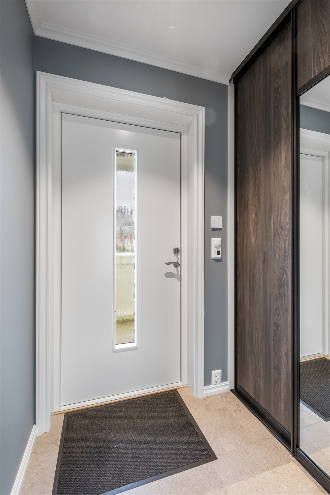 Velkommen inn til en flislagt entre med fin skyvedørsgarderobe Galleribilde