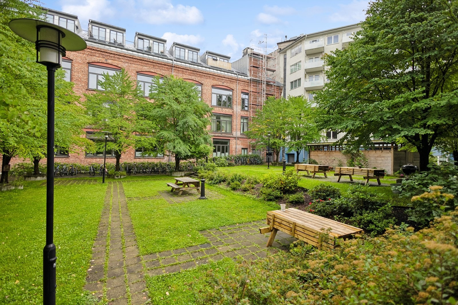 Koselig opparbeidet felles bakgård med beplantning, sykkelparkering og sittegruppe. Galleribilde