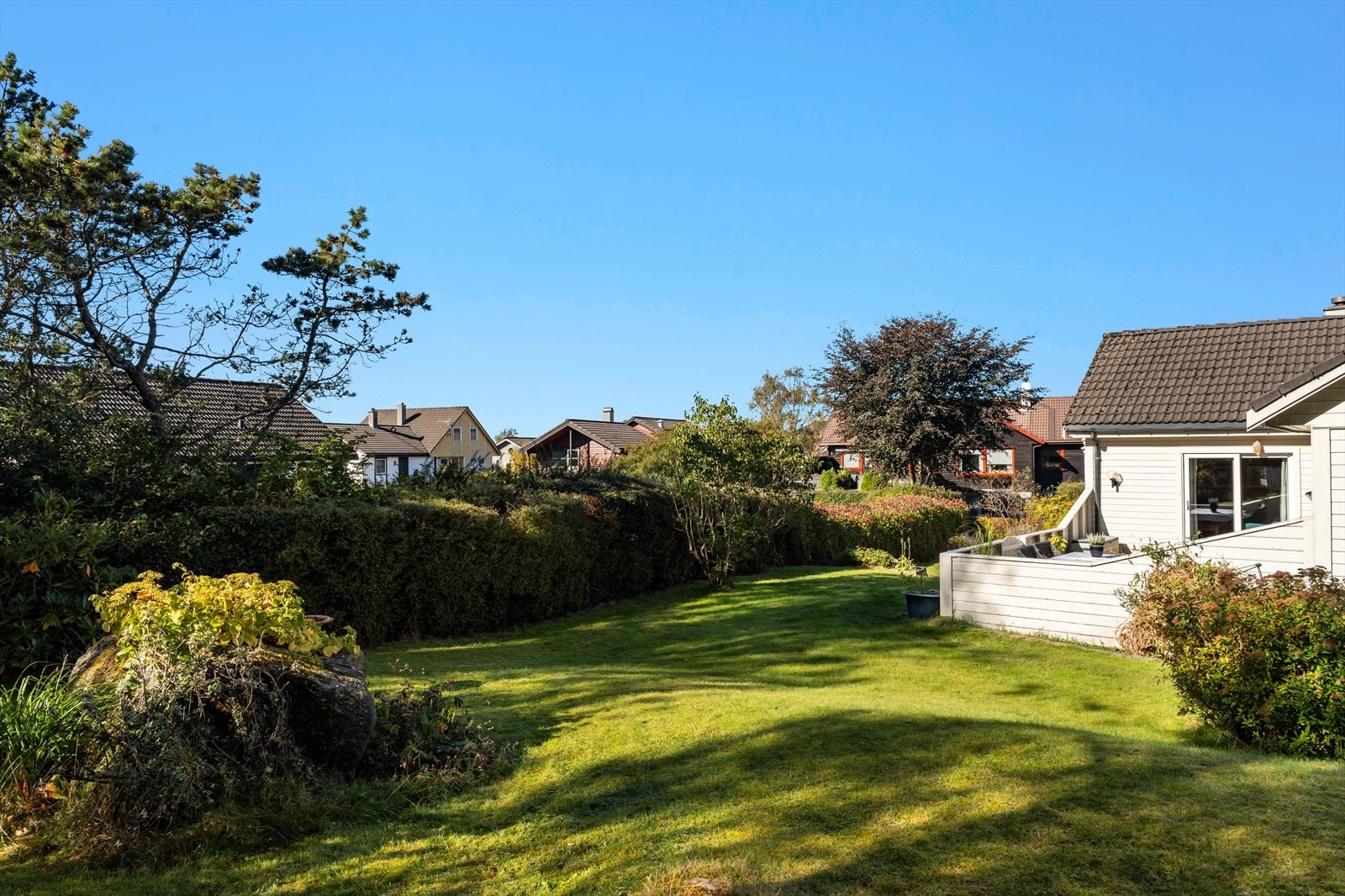 Pent opparbeidet og beplantet eiendom med stor plen, skjermende hekkbeplantning og prydbusker. Galleribilde