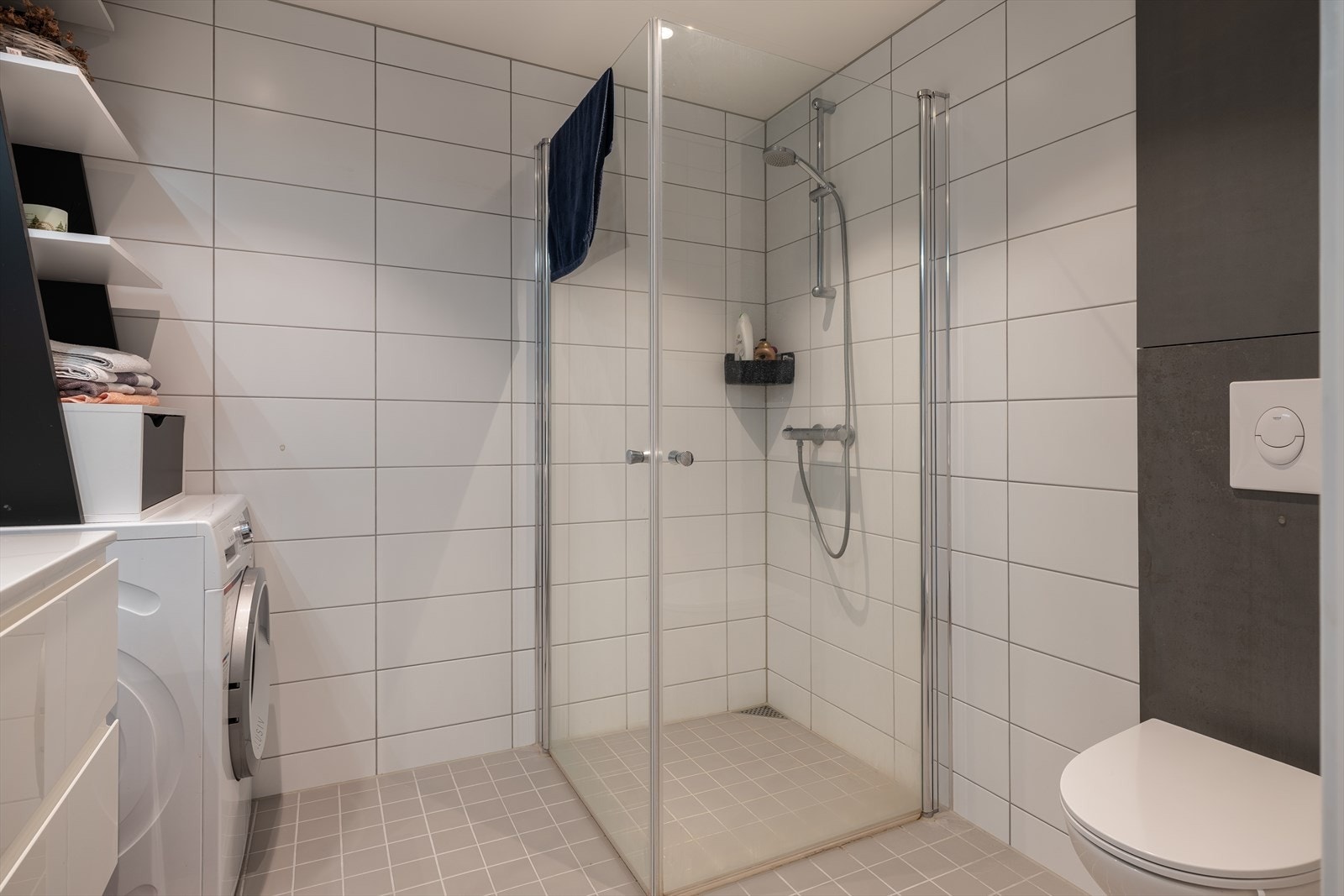 Badet er utstyrt med servant i servantskap, veggmontert toalett, innfellbare dusjdører og opplegg for vaskemaskin. Galleribilde