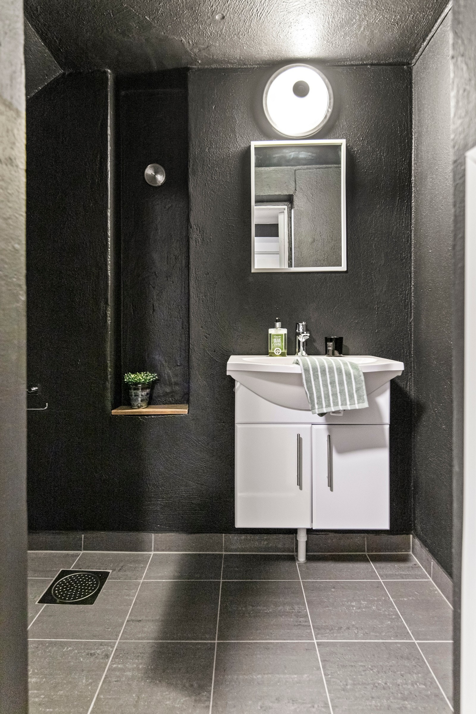 I kjelleren finner du toalettrom nummer to, som har en karakteristisk og moderne stil. Med sortmalte murvegger og grå fliser på gulvet, er dette rommet både robust og stilig. Galleribilde