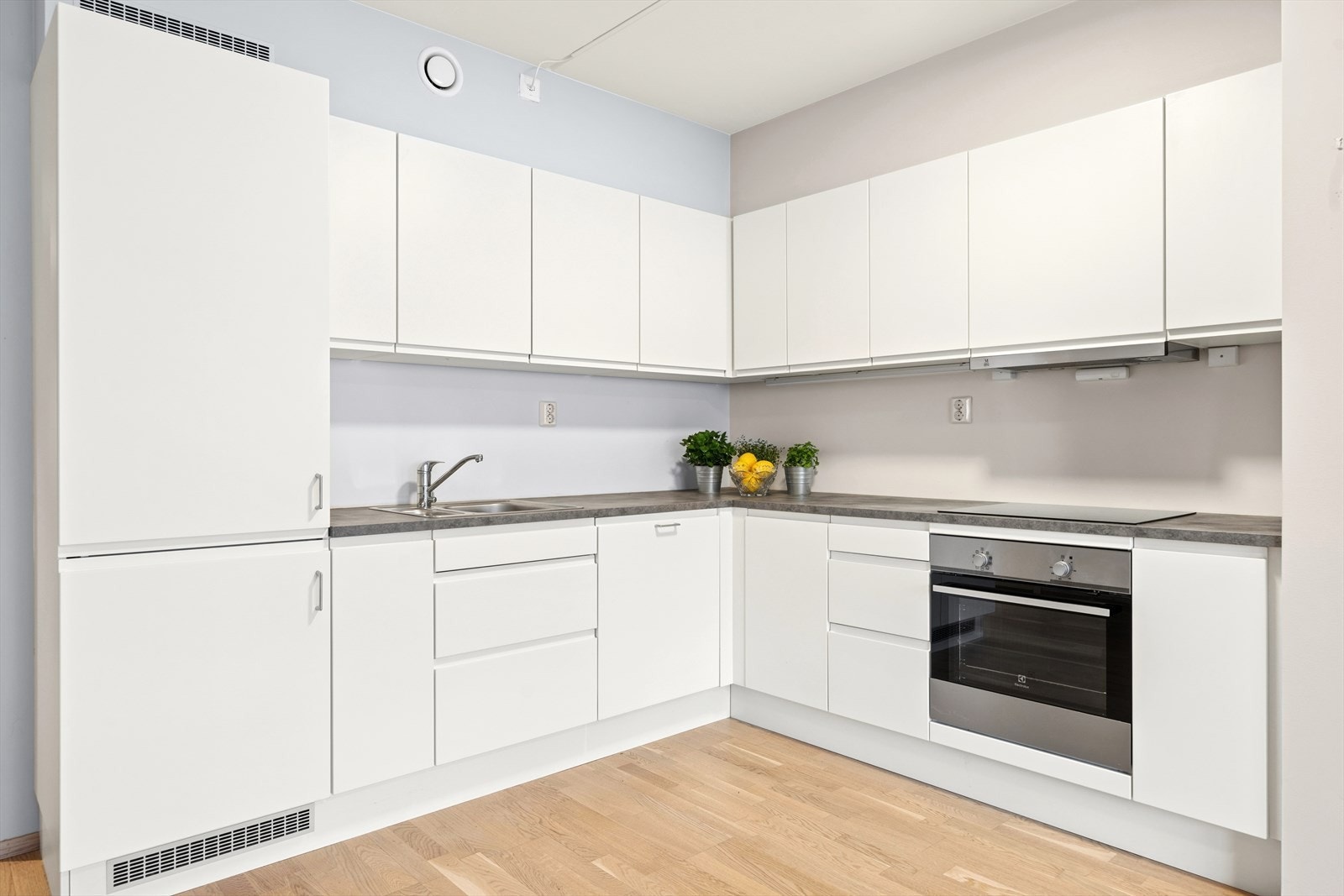 Kjøkkenet fremstår moderne og stilrent, med hvite, glatte fronter og en mørk laminert benkeplate med nedfelt kjøkkenkum. Galleribilde