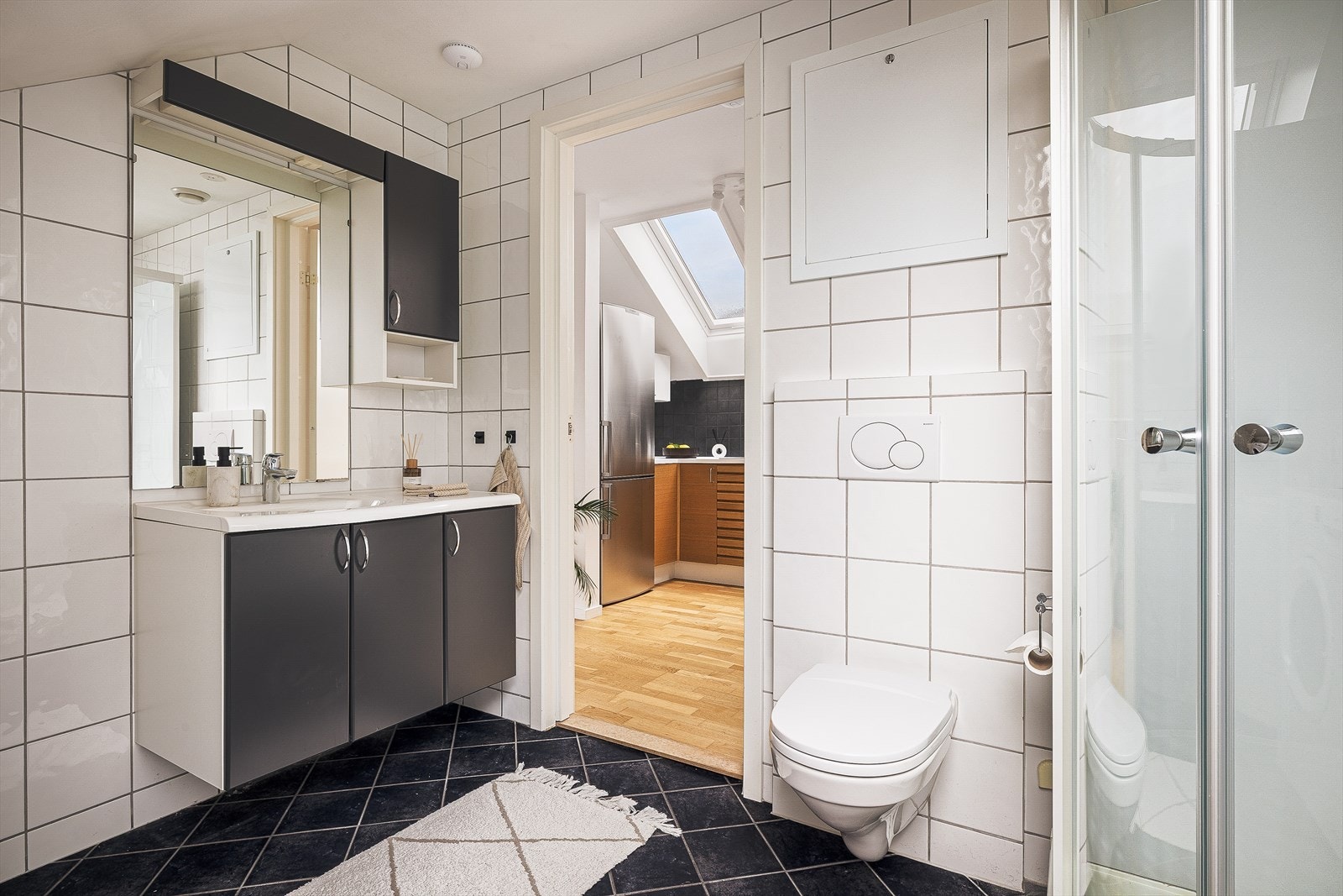 Helfliset bad med benkeskap med servant, dusjkabinett og vegghengt toalett. Galleribilde