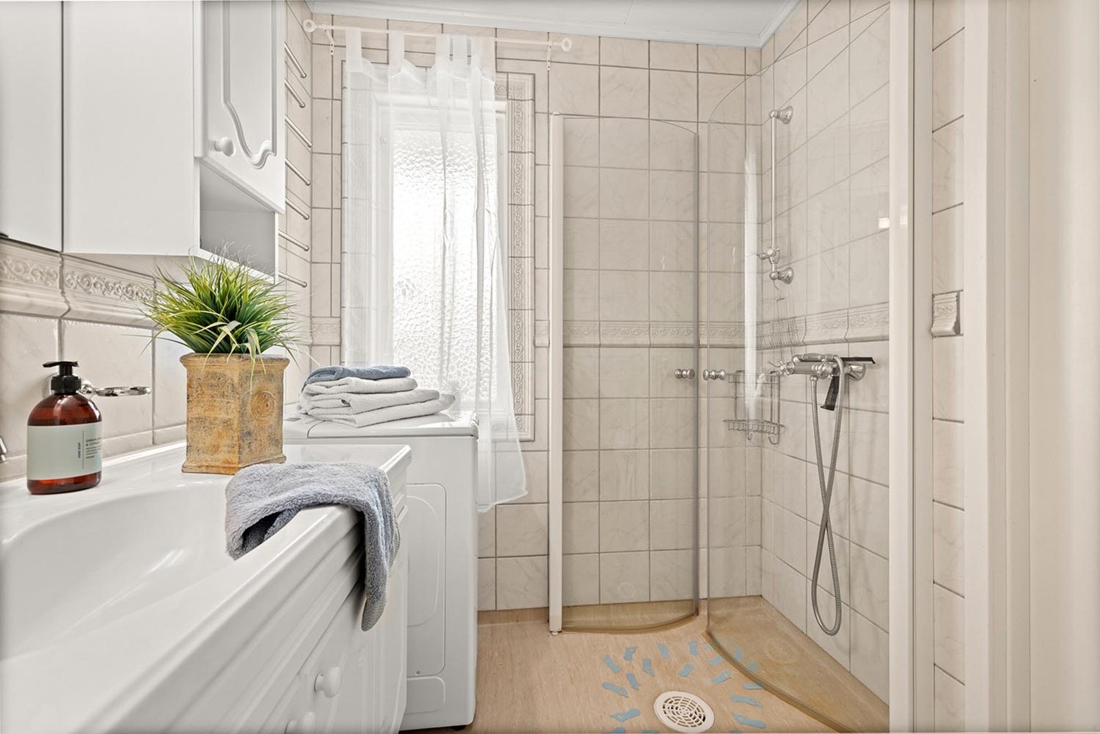 Badet er innredet med vegghengt servantinnredning med ovenpåliggende servant, speilskap med overlys og stikkontakt, høyskap, dusjhjørne med dører, gulvstående toalett og opplegg for vaskemaskin. Galleribilde