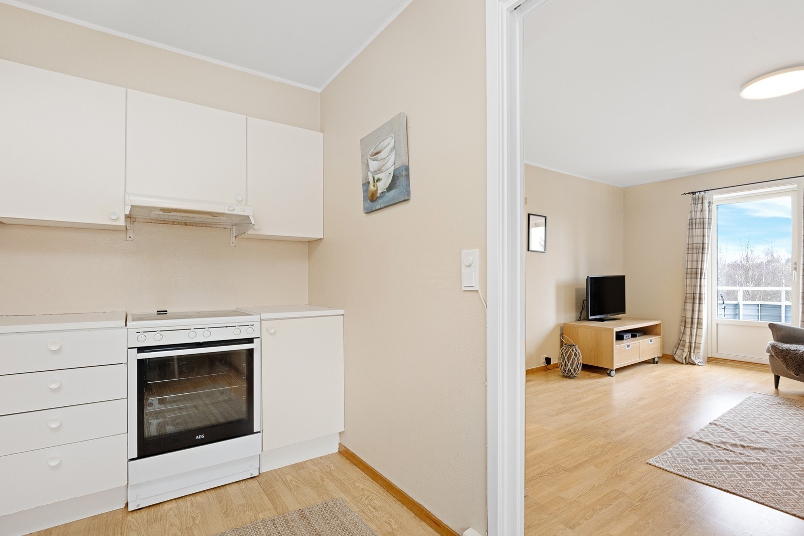 Kjøkkenet har hvite glatte fronter og laminert benkeplate, med ventilator og mekanisk avtrekk. Galleribilde