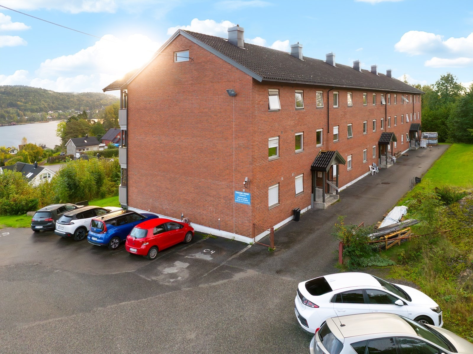 Felles, asfaltert parkeringsplass utenfor blokka. Galleribilde