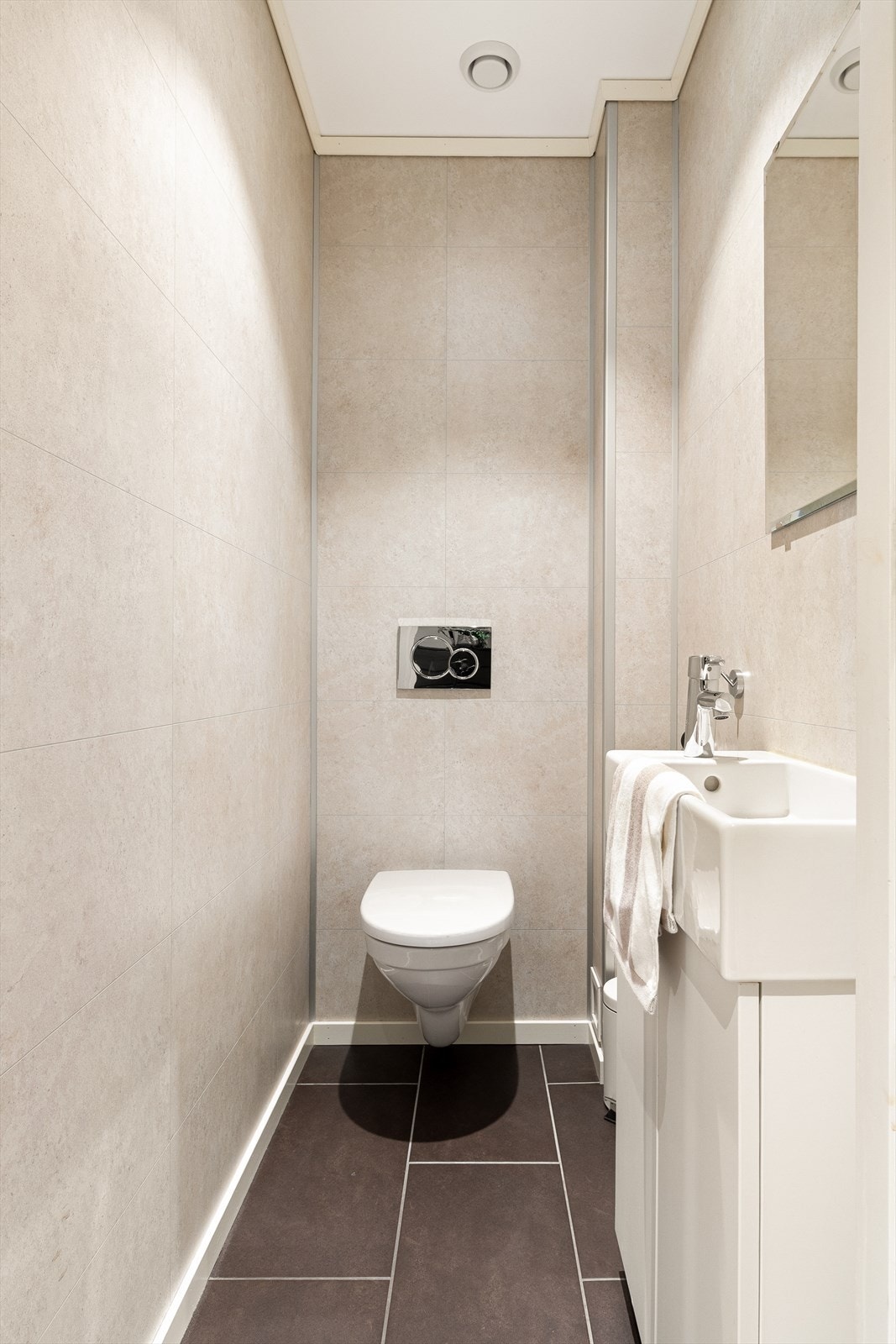 Toalettrom i tilknytning til entré. Det er baderomspanel på vegger og fliser på gulv med varmekabler. Galleribilde