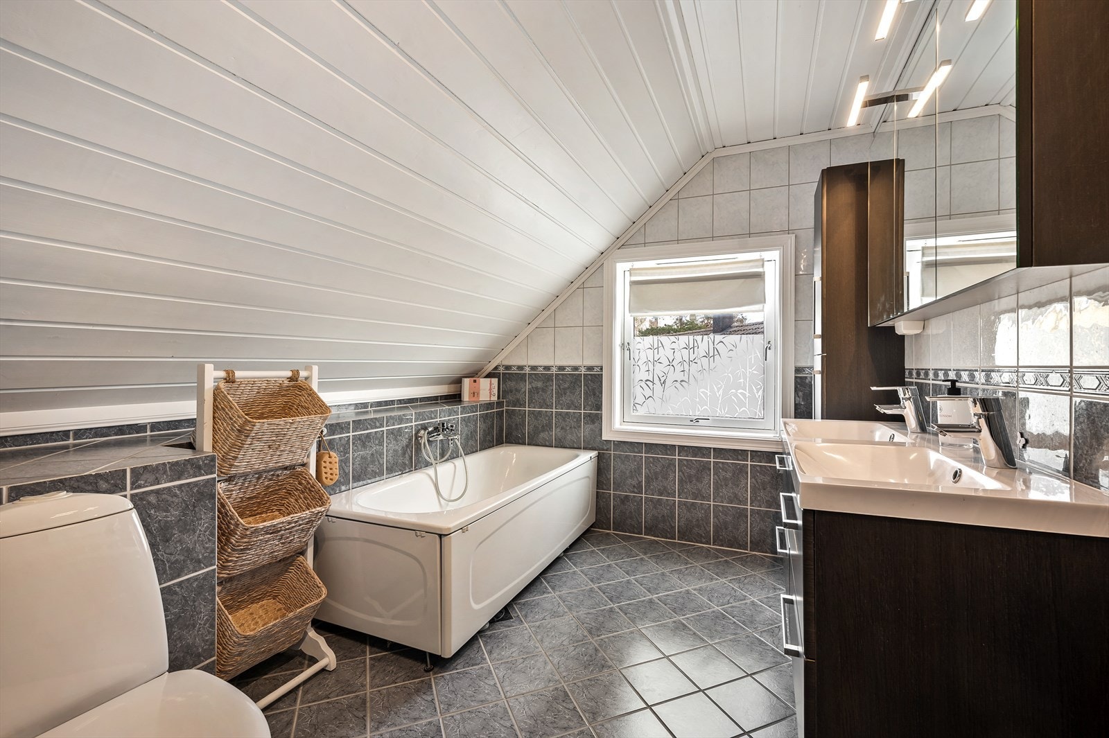 Romslig innredning med dobbel servant og overskap. Badekar. Galleribilde