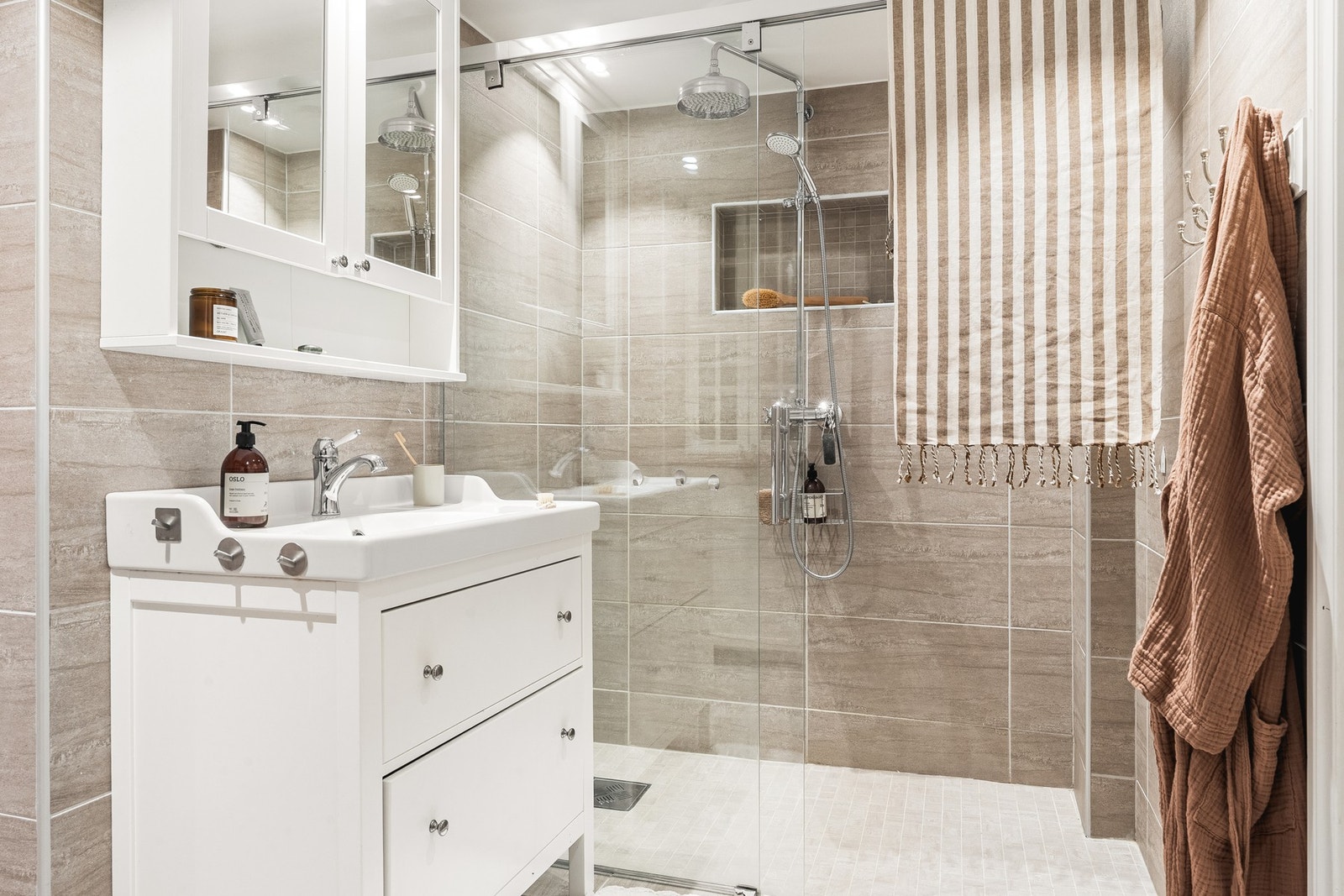 Badet har varmekabler i gulv, dusj med glassvegg, vegghengt toalett og baderomsinnredning. Galleribilde
