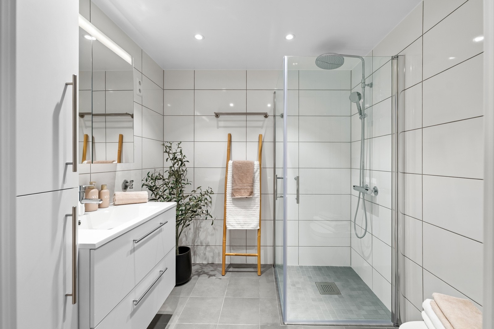 Badet er delikat og helfliset, med varme i gulv. Innredningen består av servantseksjon med skuffer, høyskap og speilskap med innfelt LED-belysning. Galleribilde