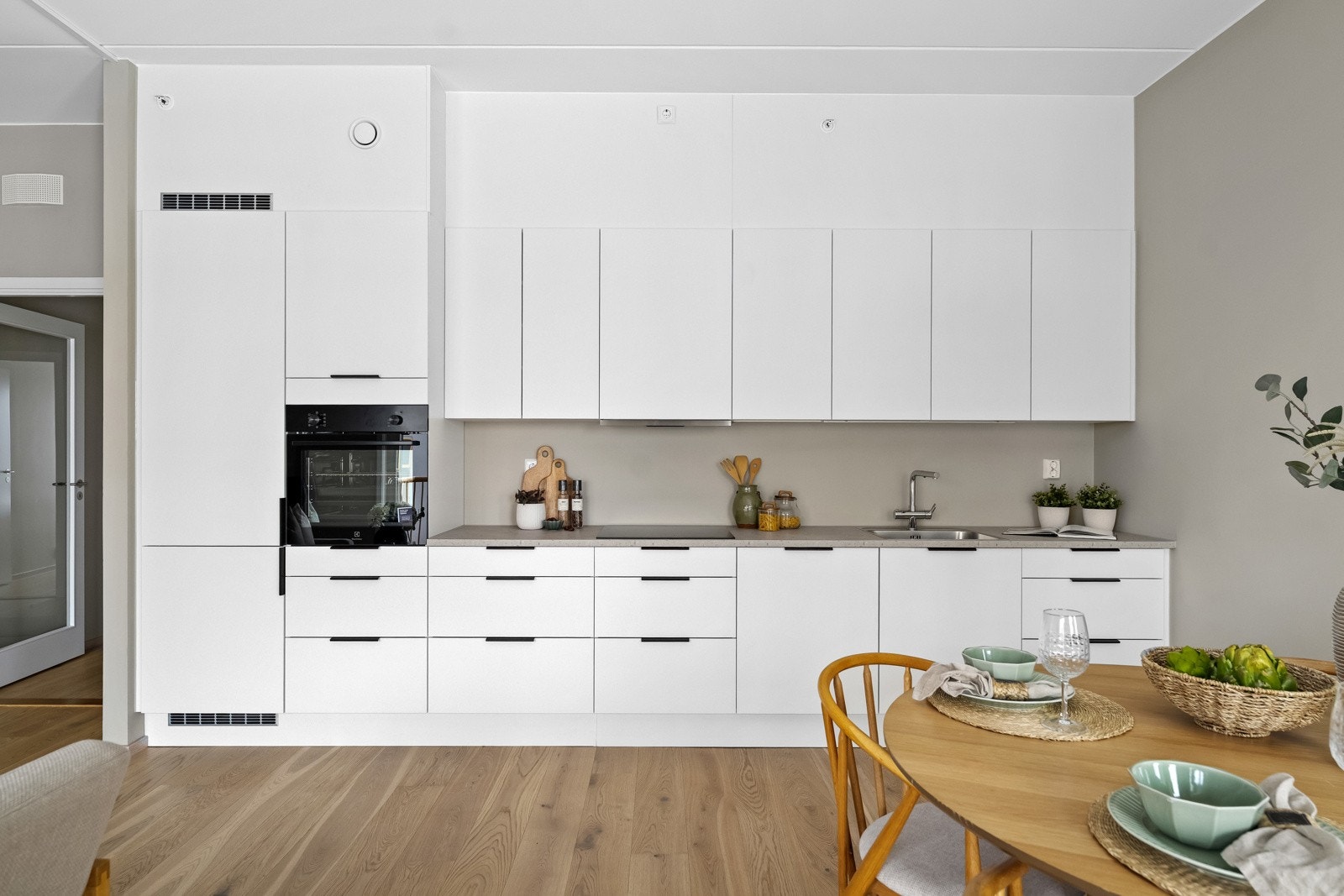 Stilrent HTH-kjøkken med lyse, slette fronter og laminat benkeplate med nedfelt vaskekum. Integrerte hvitevarer medfølger. Galleribilde