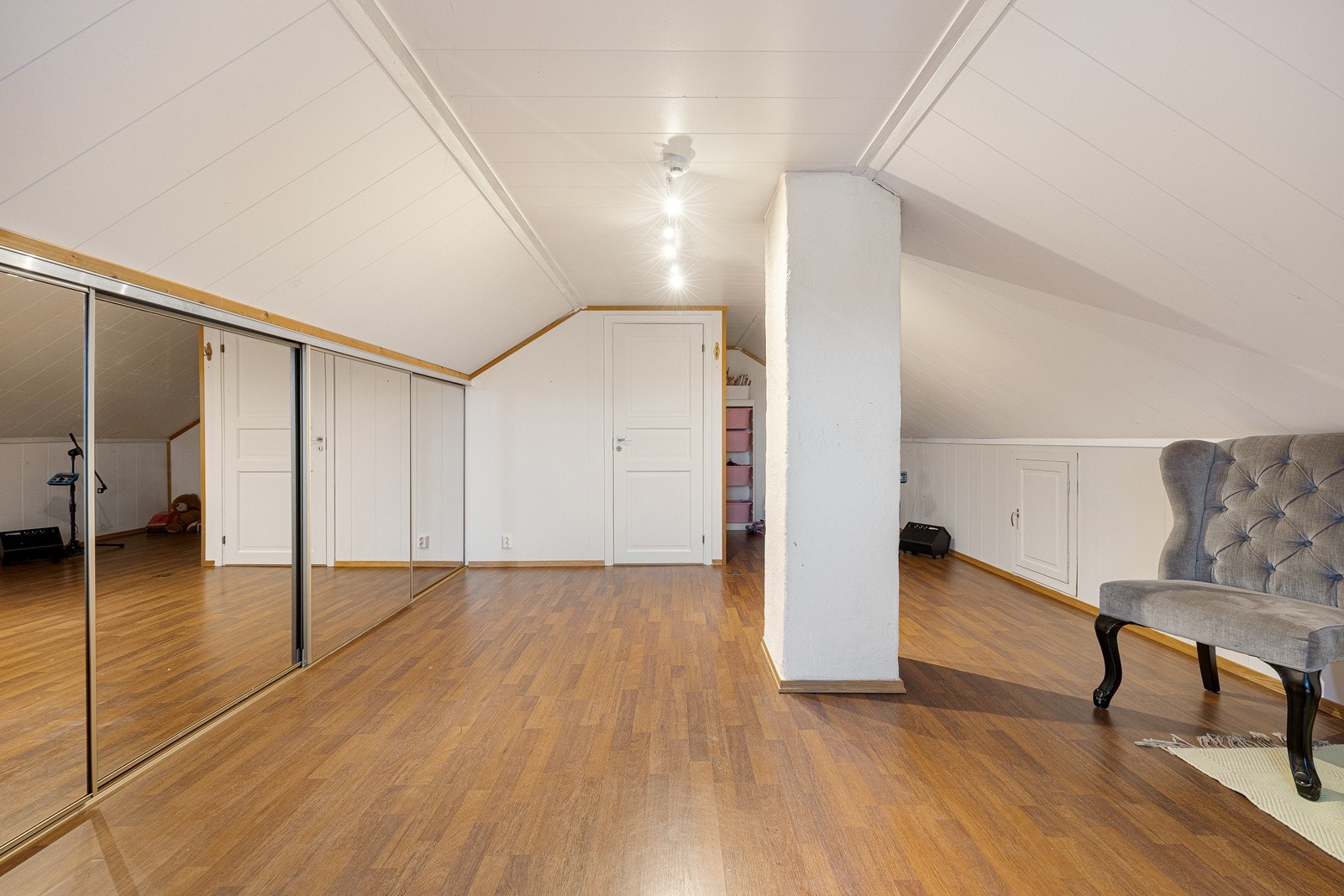 Lysmalte vegger står godt til det gyldne laminatgulvet - og langs den ene veggen er det en praktisk skyvedørsløsning med speilfronter. Galleribilde