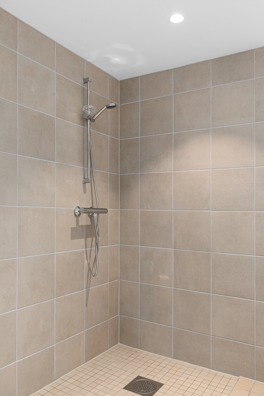 Nedsenket dusjsone med 5x5 cm fliser på gulv. Dusjarmatur leveres montert på vegg. Galleribilde