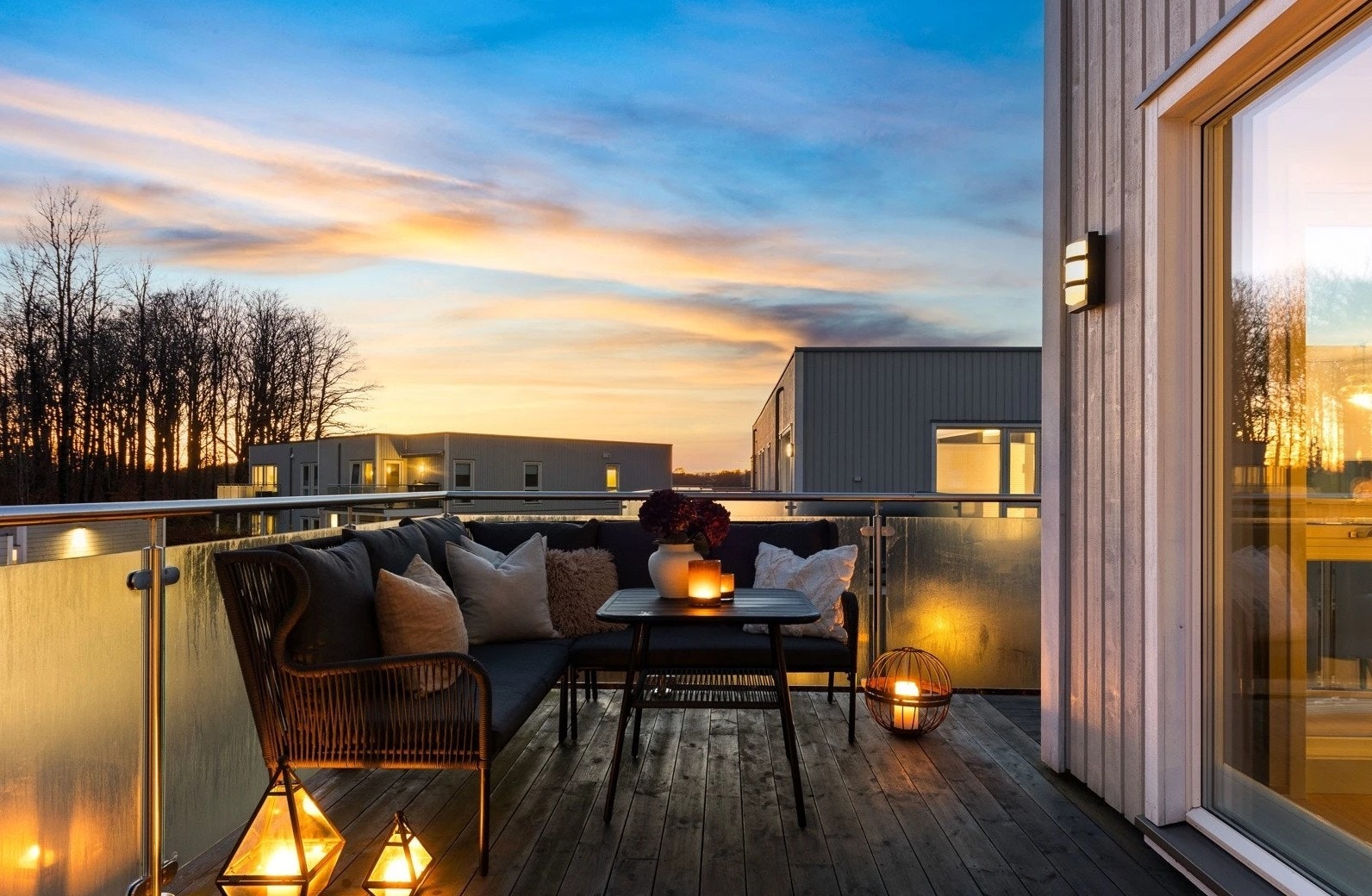 Balkongen har gulv av beisede bord og et moderne rekkverk i glass og stål. Galleribilde