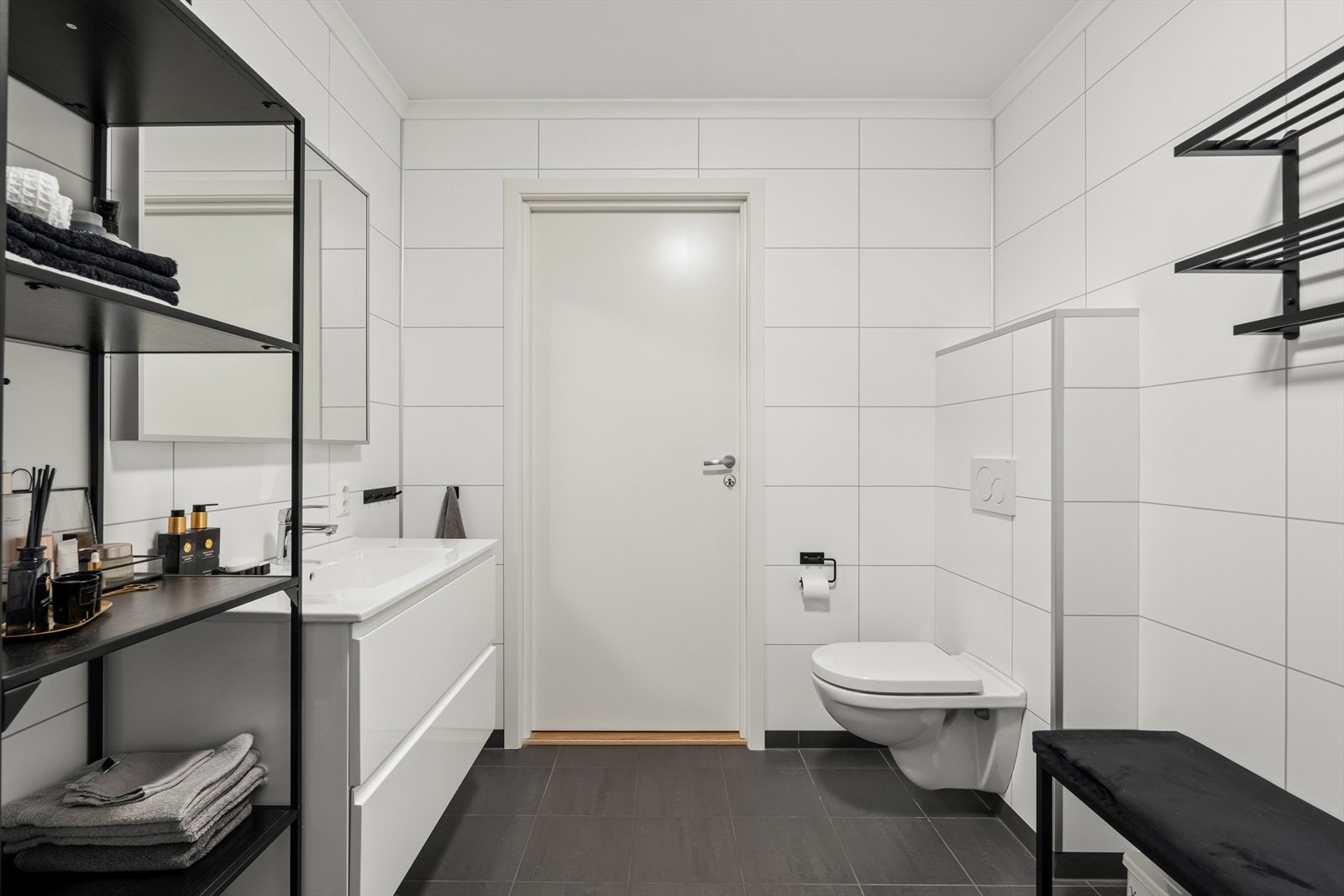 Badet er utstyrt med dusjhjørne, vegghengt toalett og servant med skapinnredning. Galleribilde