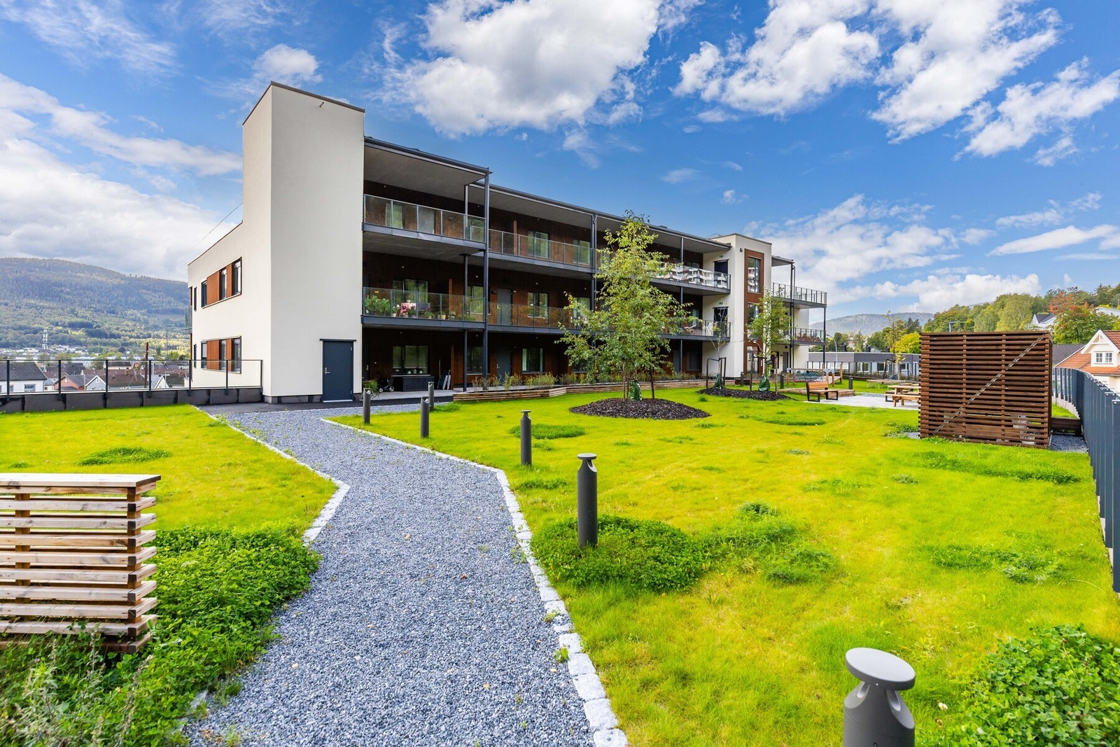 Nydelig gressplen og lys ved grusveien som lyser opp helt til inngangsdøra for boligseksjonen Galleribilde