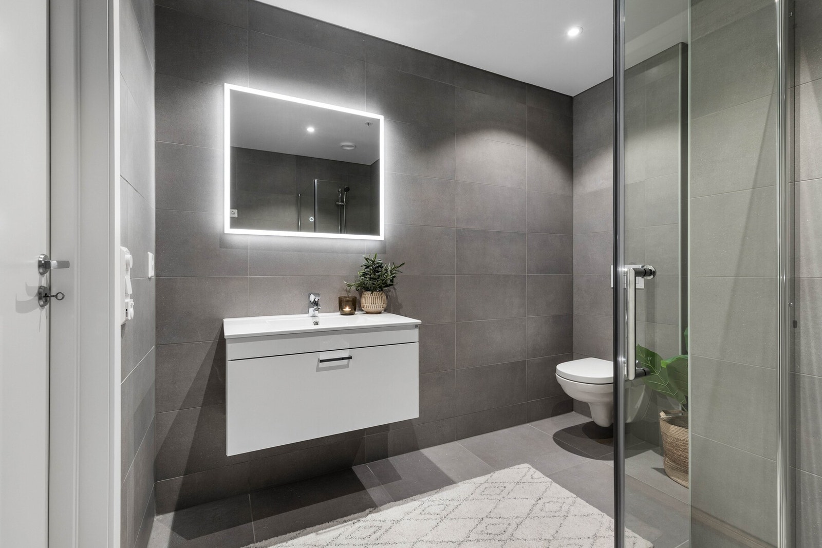 Downlights i taket og lys rundt speilet gjør dette badet til et stemningsfullt miljø Galleribilde