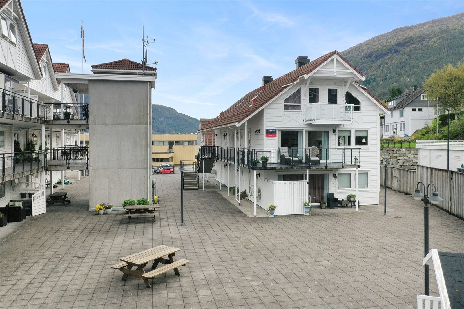 Utenfor leiligheten er det et romslig steinlagt fellesområde med lekehytte og parkbenker. Galleribilde