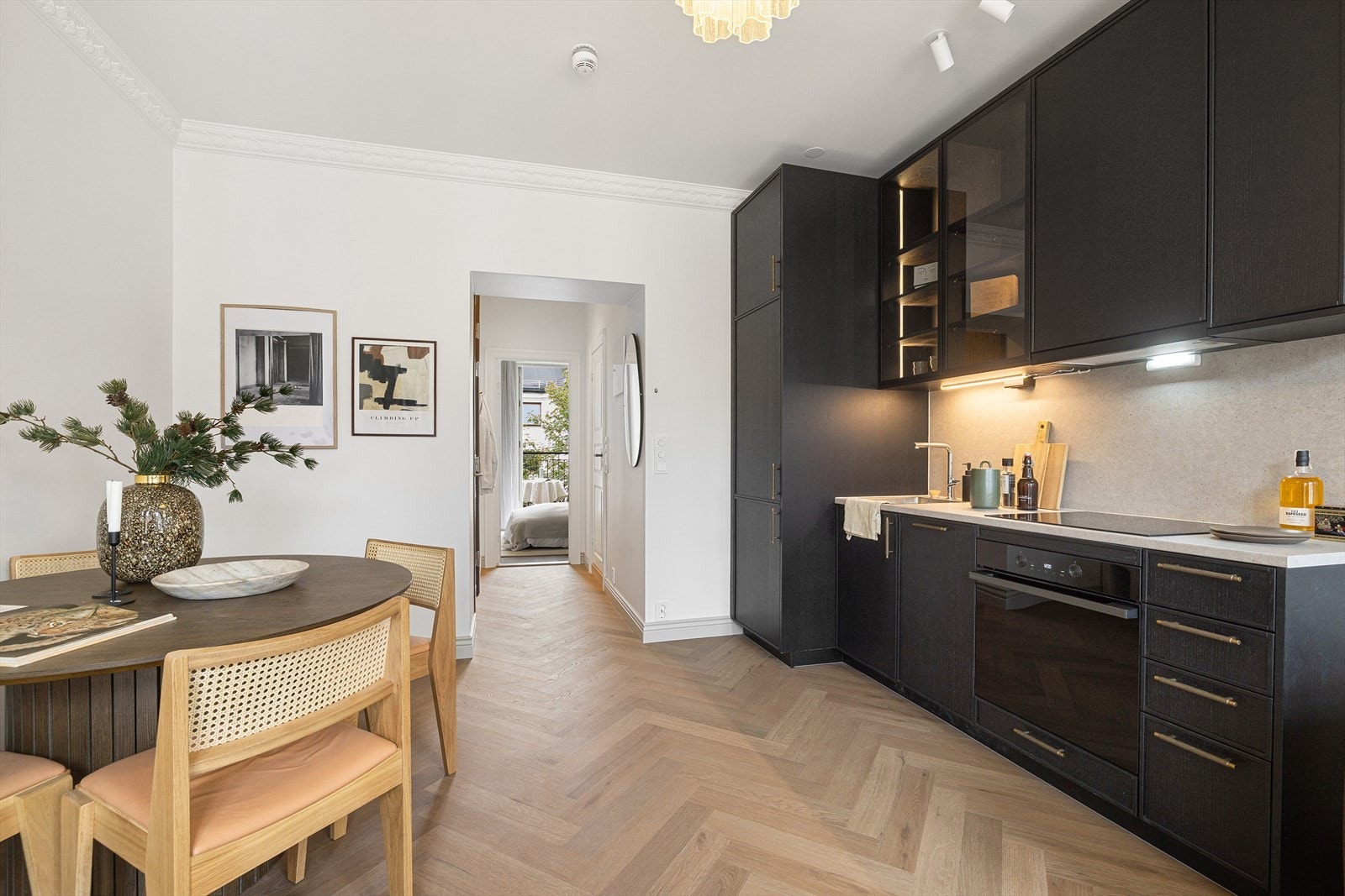 Kjøkkeninnredning har beiset fronter, laminat benkeplate, oppvaskkum i stål og kjøkkenplate over benk. Galleribilde